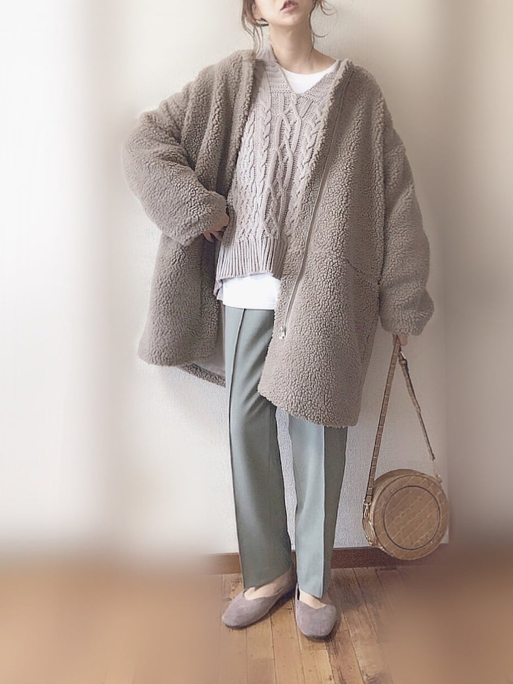 ブラウン系のノーカラーコート、ベージュ系のニット/セーター、ホワイト系のTシャツ/カットソーを着用したレディースの冬コーディネートの1枚目の写真