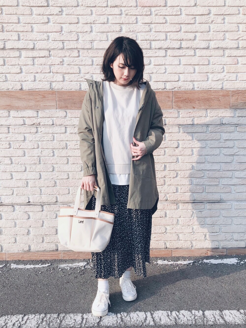 ベージュ系のTシャツ/カットソー、グリーン系のミリタリージャケット、ホワイト系のスニーカーを着用したレディースの春コーディネートの1枚目の写真
