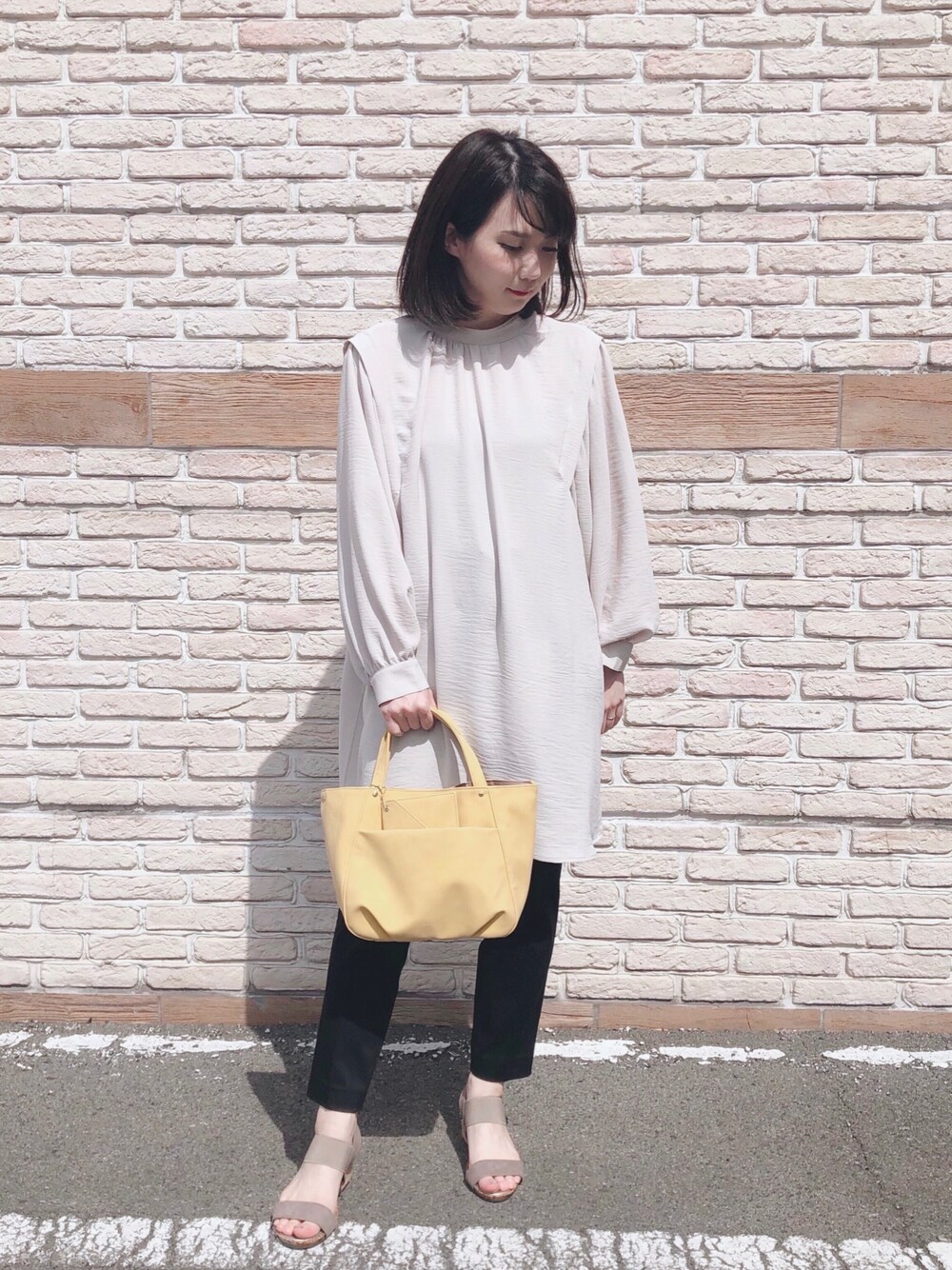 ベージュ系のチュニック、ブラック系のその他パンツ、ベージュ系のサンダルを着用したレディースの春コーディネートの1枚目の写真