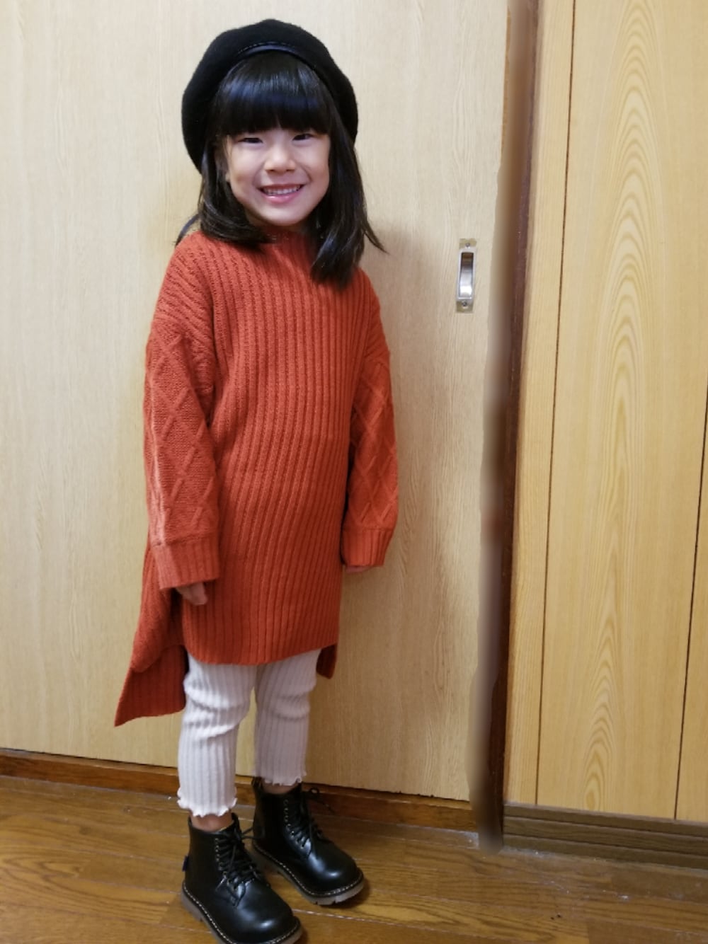 オレンジ系のワンピース、ベージュ系のその他パンツ、ブラック系のブーツを着用したキッズの秋コーディネートの1枚目の写真