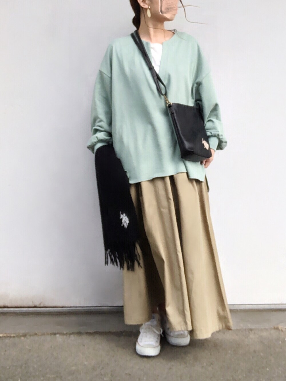 グリーン系のTシャツ/カットソー、ベージュ系のスカート、ブラック系のショルダーバッグを着用したレディースの冬コーディネートの1枚目の写真