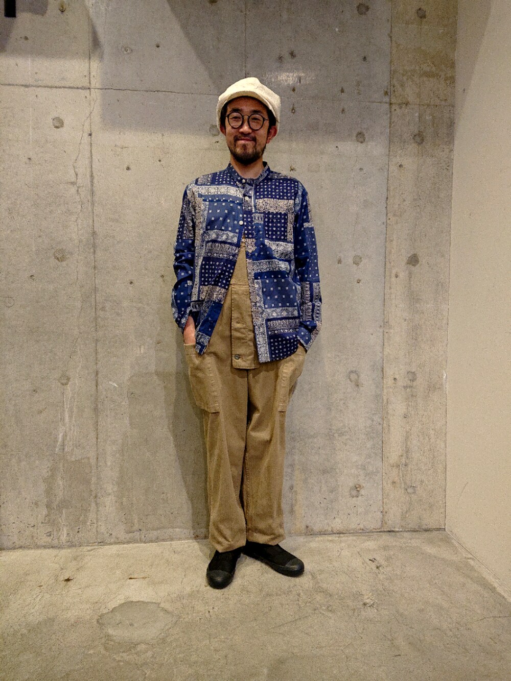 ベージュ系のサロペット/オーバーオール、ブラック系のスニーカー、ホワイト系のキャスケットを着用したメンズの春コーディネートの1枚目の写真