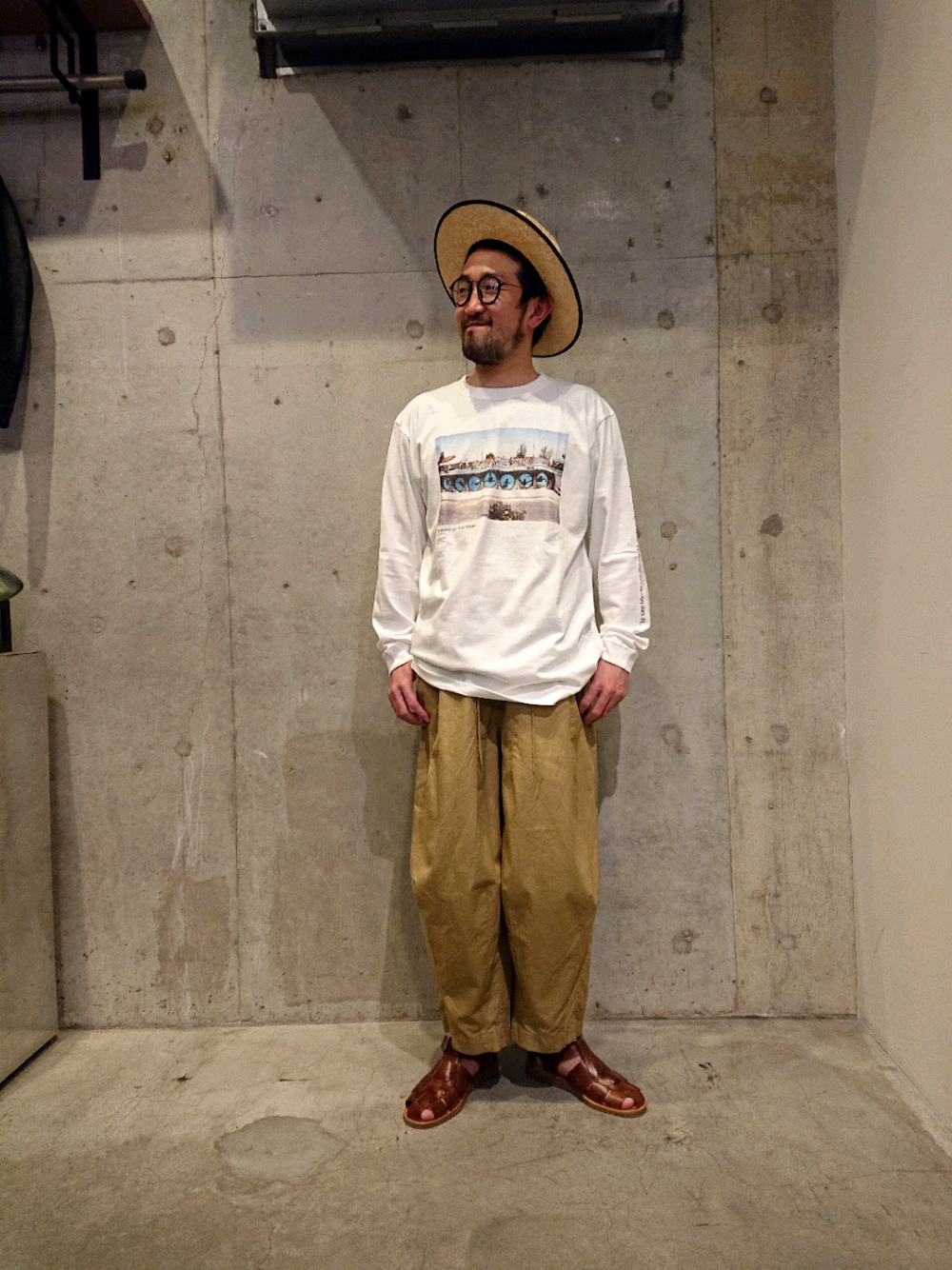 ホワイト系のTシャツ/カットソー、ブラウン系のサンダル、ベージュ系のハットを着用したメンズの春コーディネートの1枚目の写真