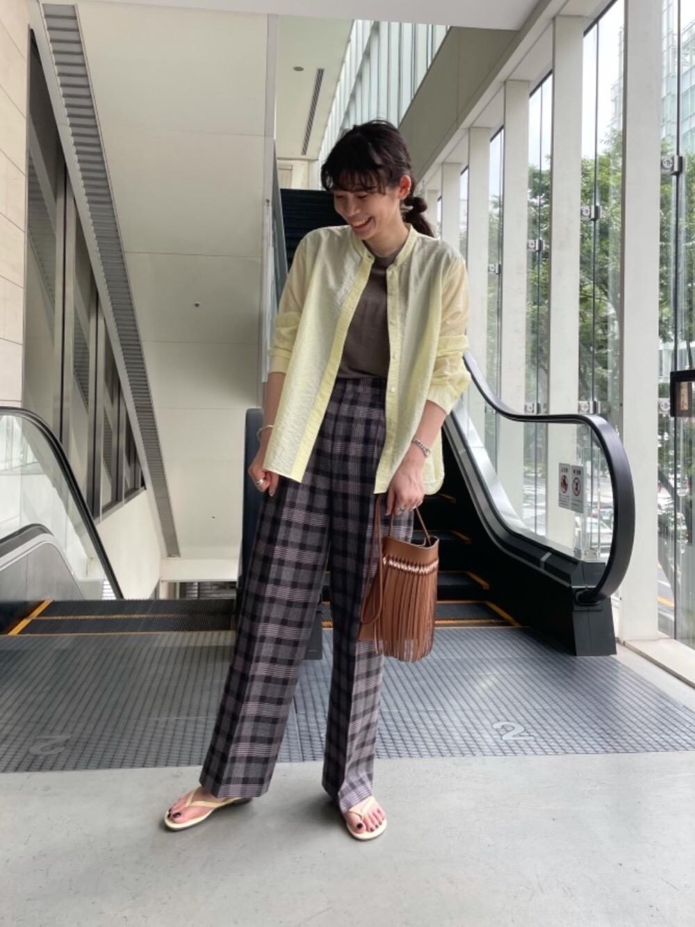 ブラウン系のショルダーバッグ、ブラック系のその他パンツ、イエロー系のシャツ/ブラウスを着用したレディースの夏コーディネートの1枚目の写真