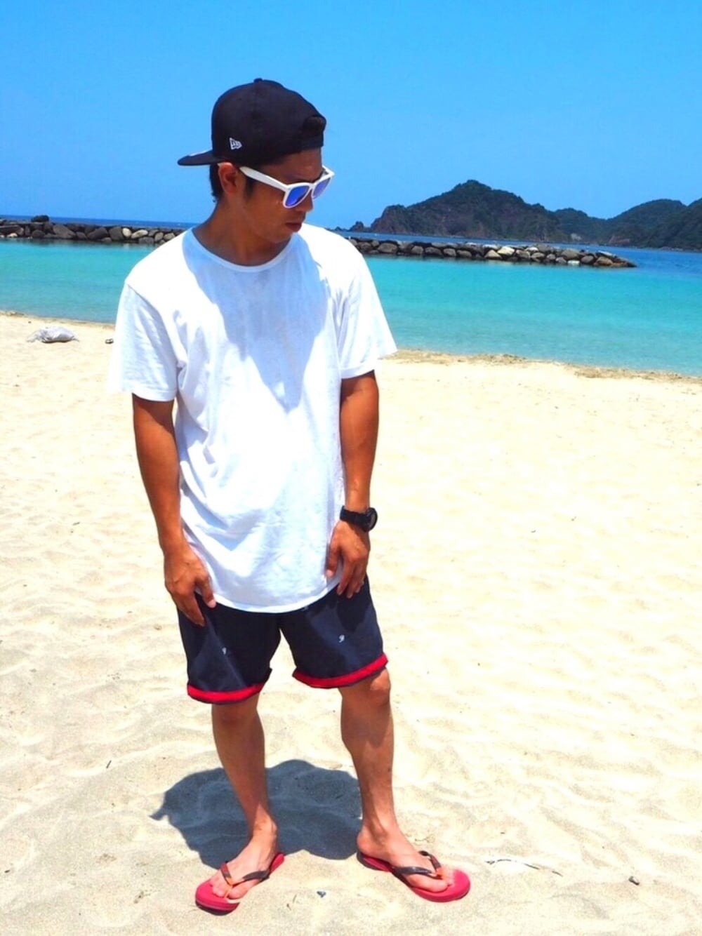 ホワイト系のTシャツ/カットソー、レッド系のサンダル、ブルー系のキャップを着用したメンズの夏コーディネートの1枚目の写真