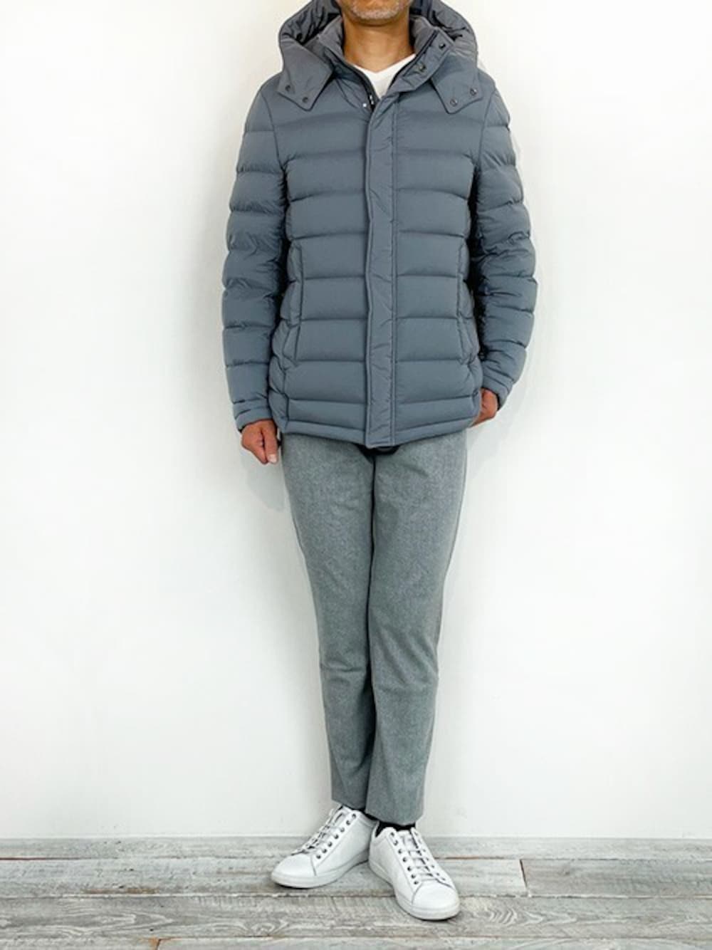 グレー系のダウンジャケット/コート、ホワイト系のニット/セーター、ホワイト系のスニーカーを着用したメンズの冬コーディネートの1枚目の写真