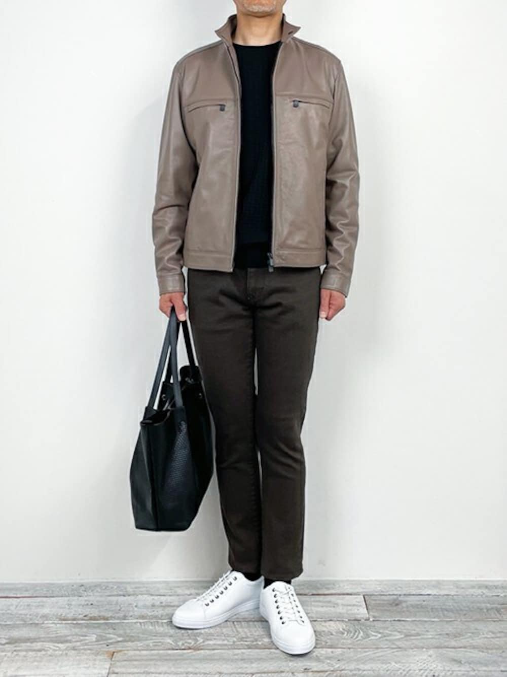 ブラック系のニット/セーター、ベージュ系のデニムパンツ、ホワイト系のスニーカーを着用したメンズの冬コーディネートの1枚目の写真