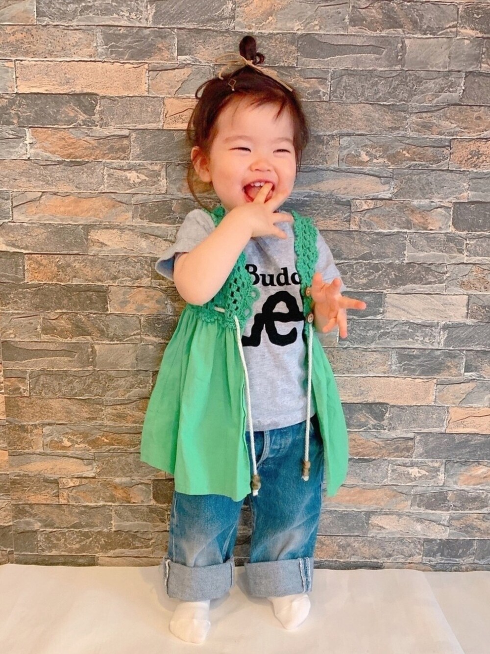 グリーン系のベスト、グレー系のTシャツ/カットソー、ブルー系のデニムパンツを着用したキッズの春コーディネートの1枚目の写真