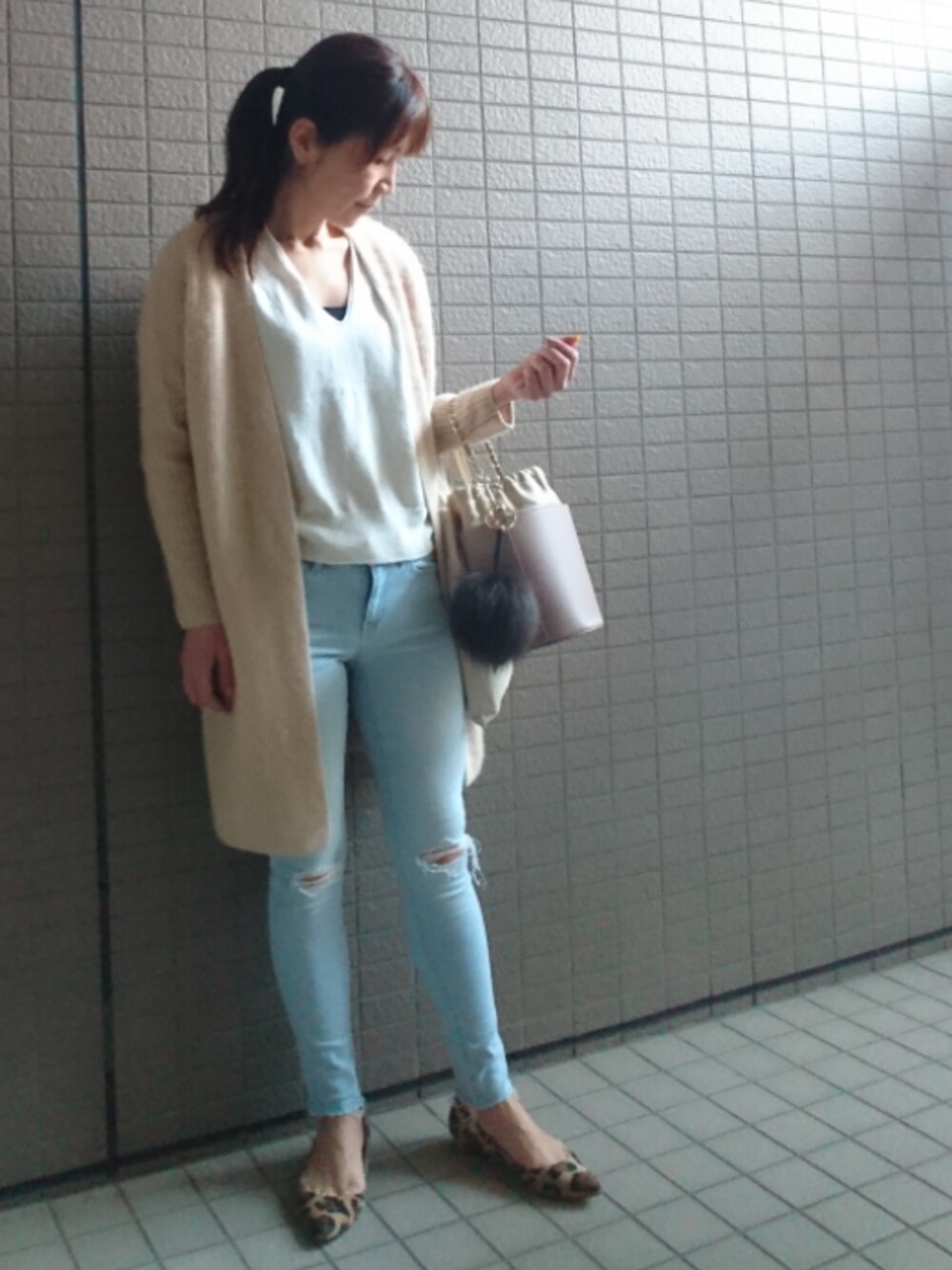 ホワイト系のカーディガン/ボレロ、ホワイト系のニット/セーター、ピンク系のショルダーバッグを着用したレディースの春コーディネートの1枚目の写真