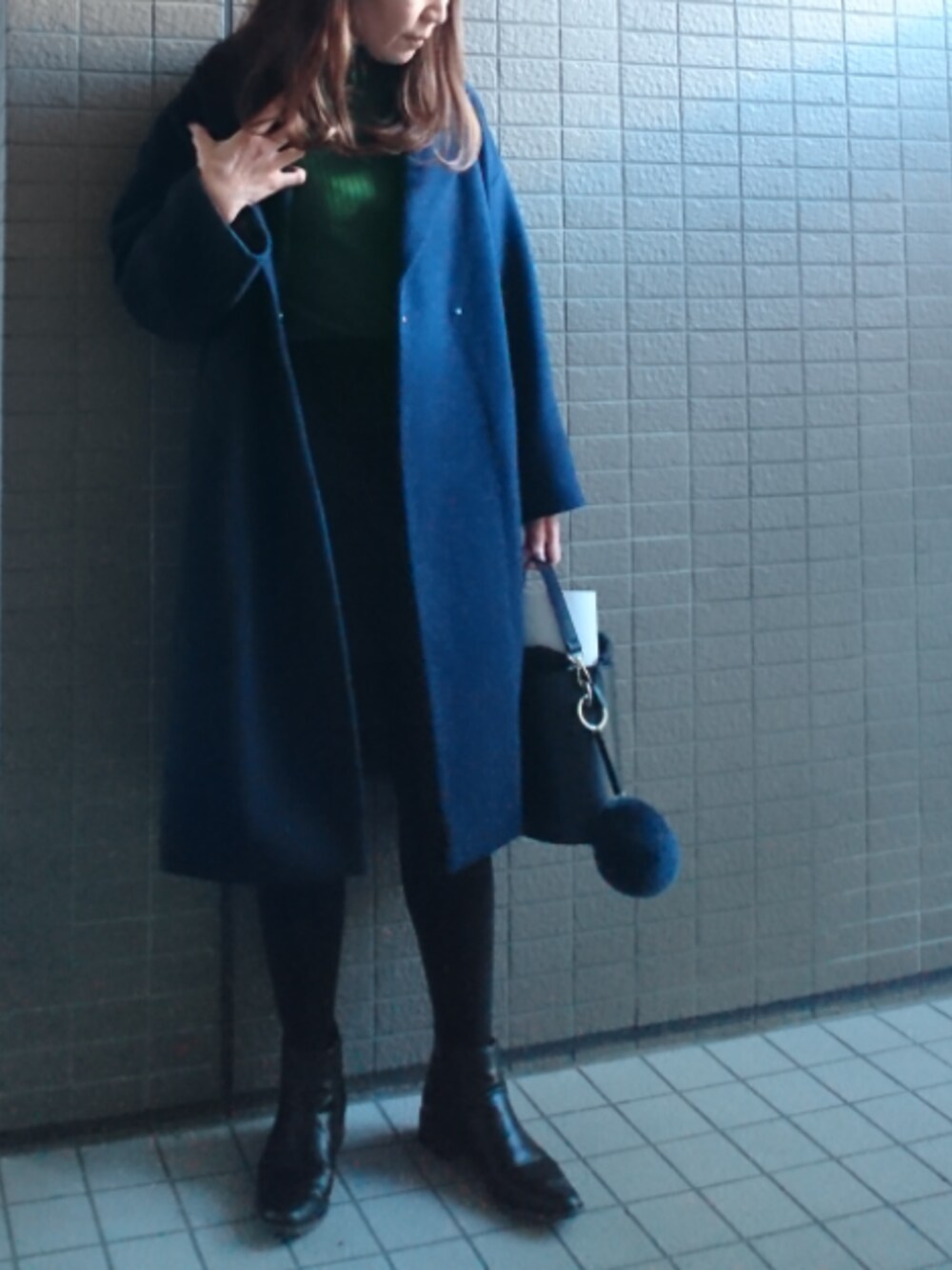 ブルー系のチェスターコート、グリーン系のニット/セーター、ブルー系のスカートを着用したレディースの冬コーディネートの1枚目の写真