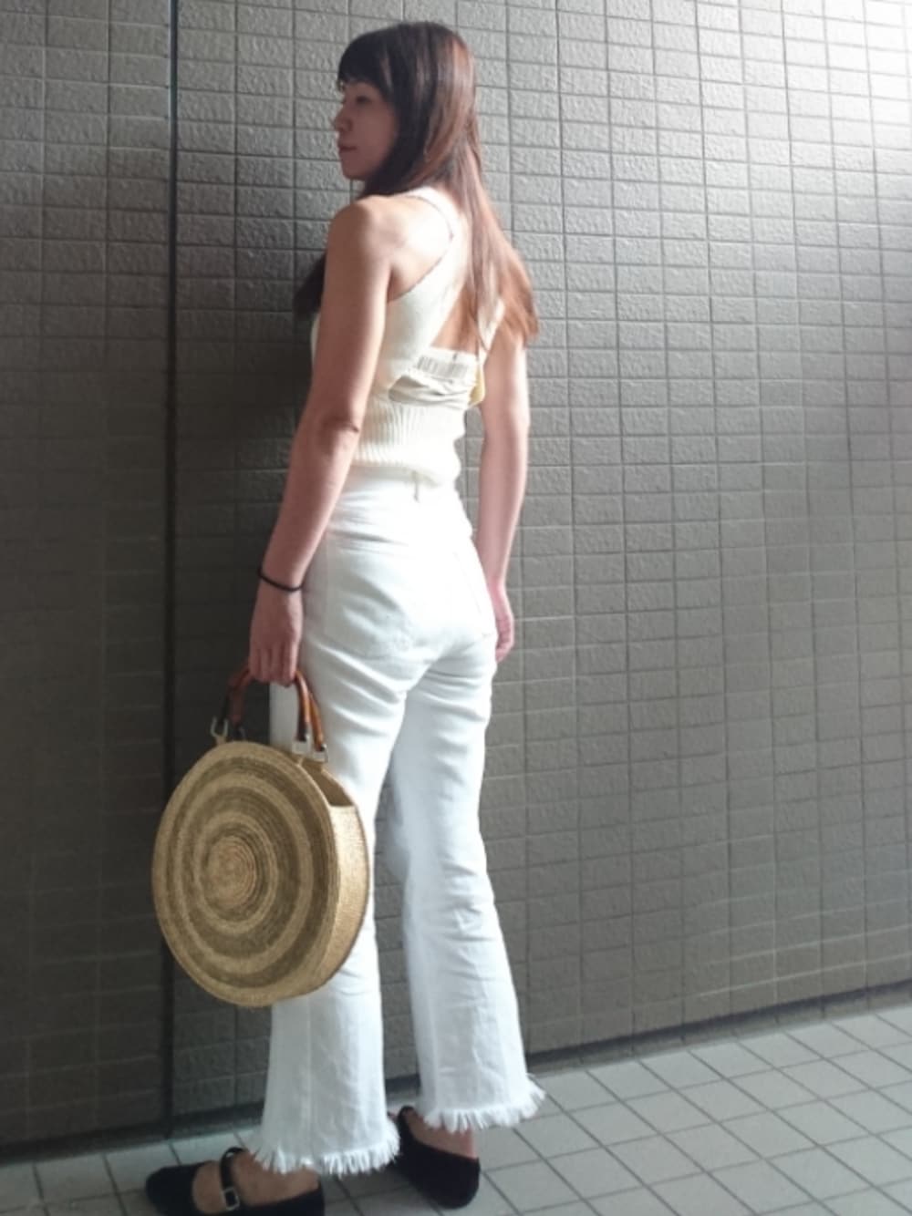 ホワイト系のタンクトップ、ホワイト系のデニムパンツ、ブラウン系のかごバッグを着用したレディースの夏コーディネートの1枚目の写真