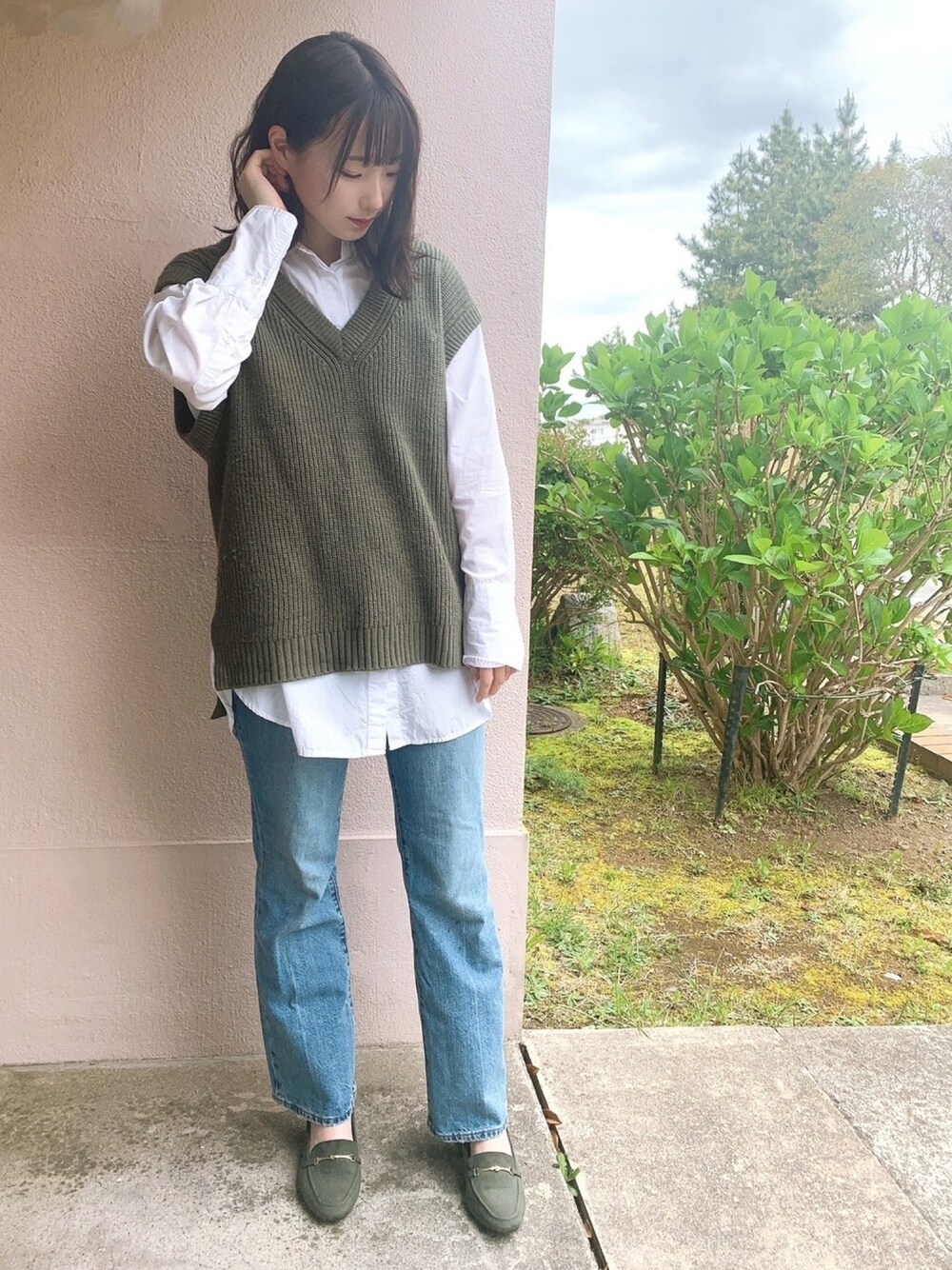 ホワイト系のトップス、グリーン系のベスト、ブルー系のパンツを着用したレディースの春コーディネートの1枚目の写真