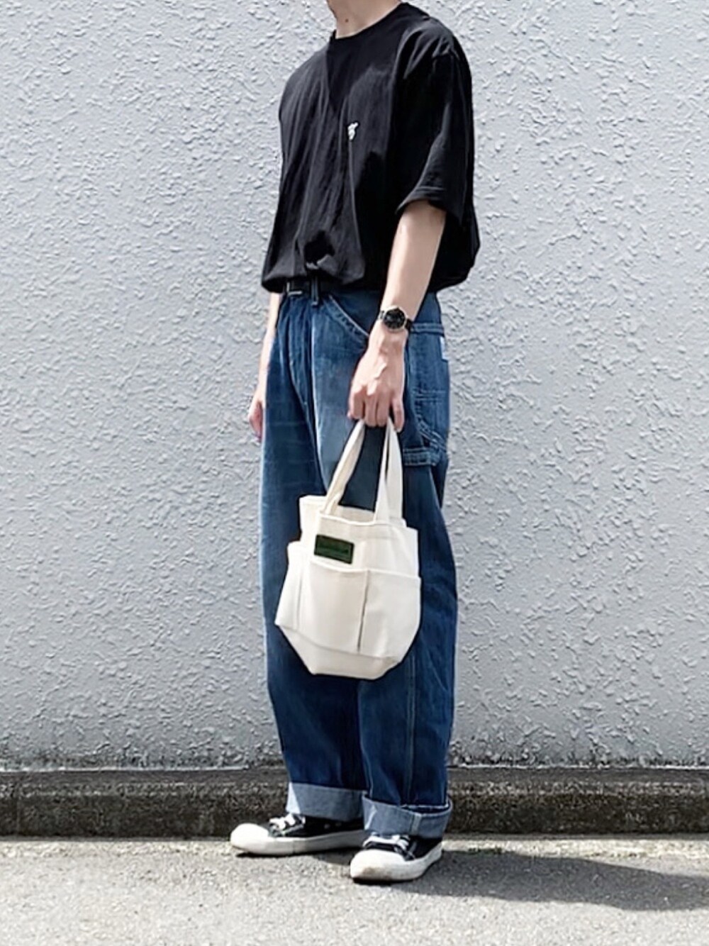 ブラック系のTシャツ/カットソー、ブルー系のデニムパンツ、ブラック系のスニーカーを着用したメンズの春コーディネートの1枚目の写真