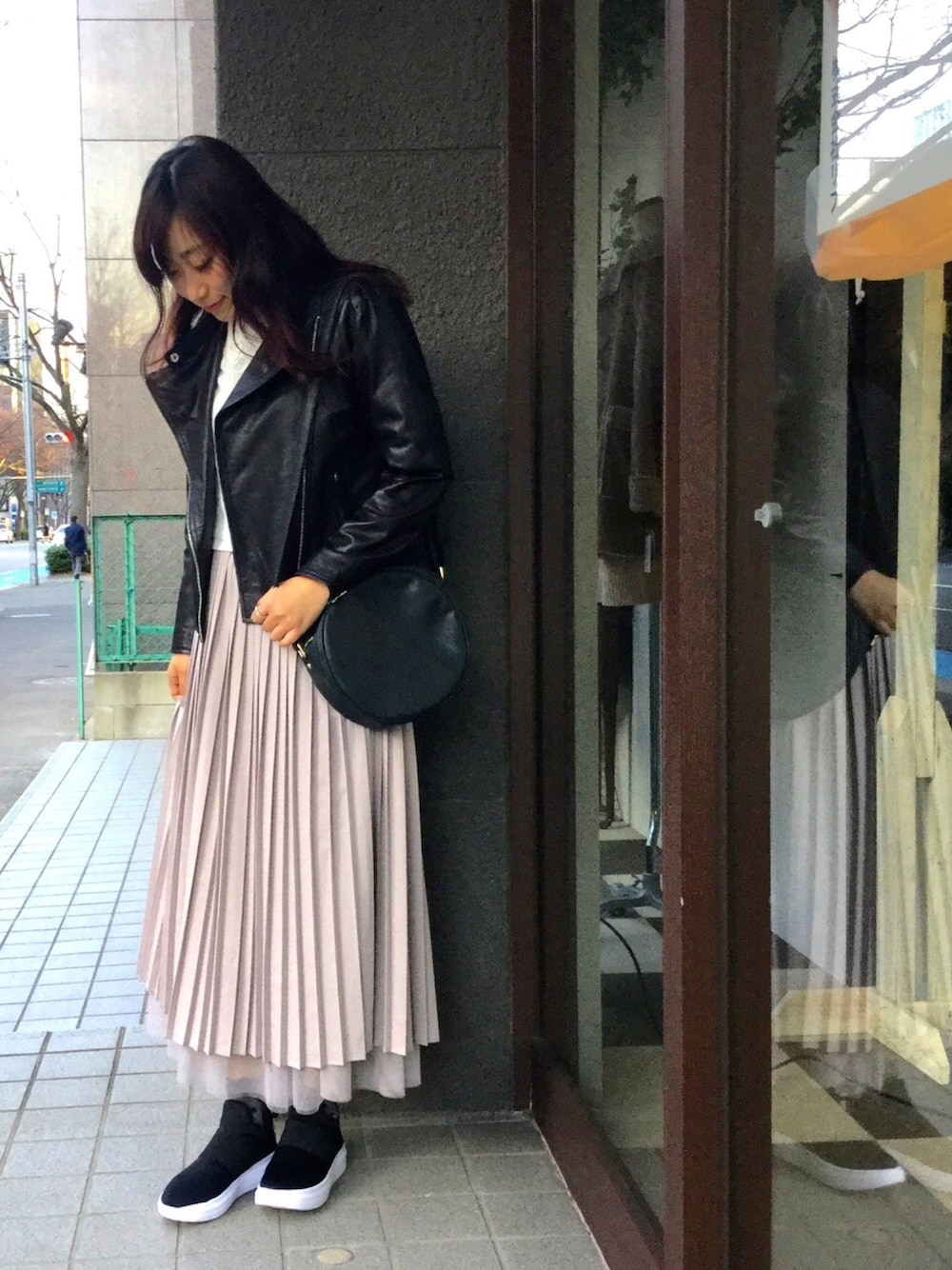 ブラック系のライダースジャケット、グレー系のスカートを着用したレディースの冬コーディネートの1枚目の写真