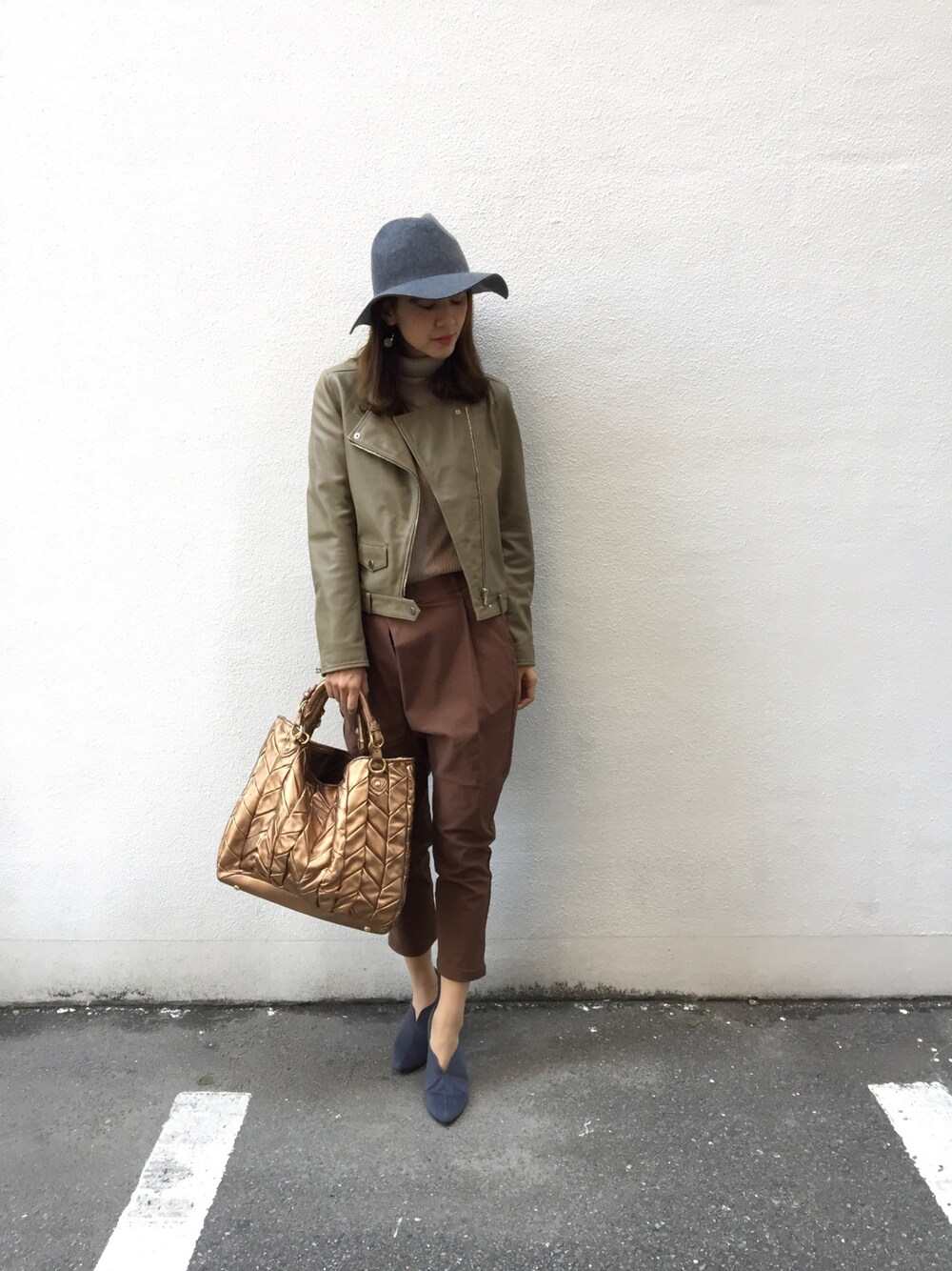 グリーン系のライダースジャケット、ブラウン系のパンツ、グレー系のブーティを着用したレディースの秋コーディネートの1枚目の写真