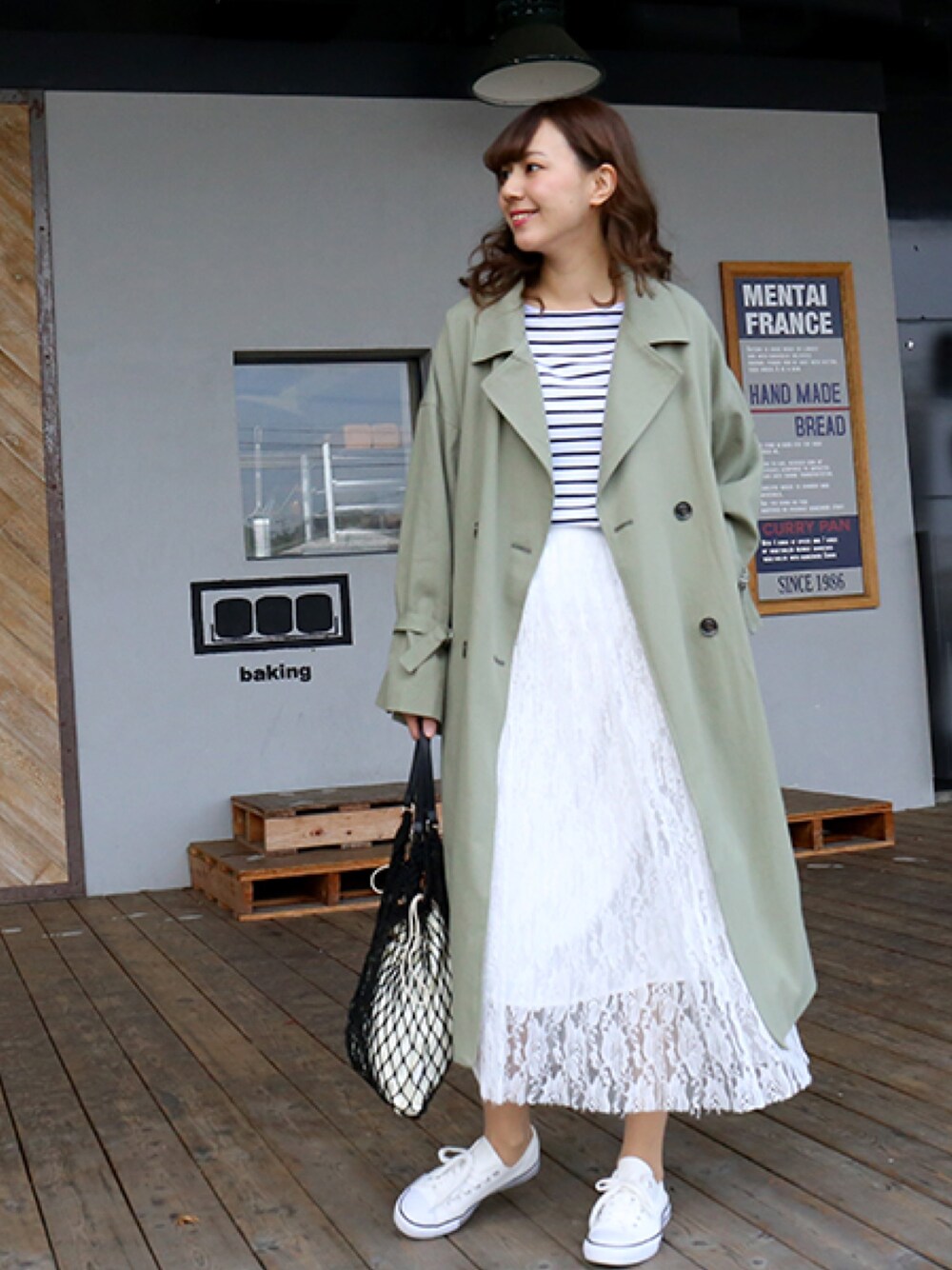 グリーン系のトレンチコート、ホワイト系のTシャツ/カットソー、ホワイト系のスカートを着用したレディースの冬コーディネートの1枚目の写真