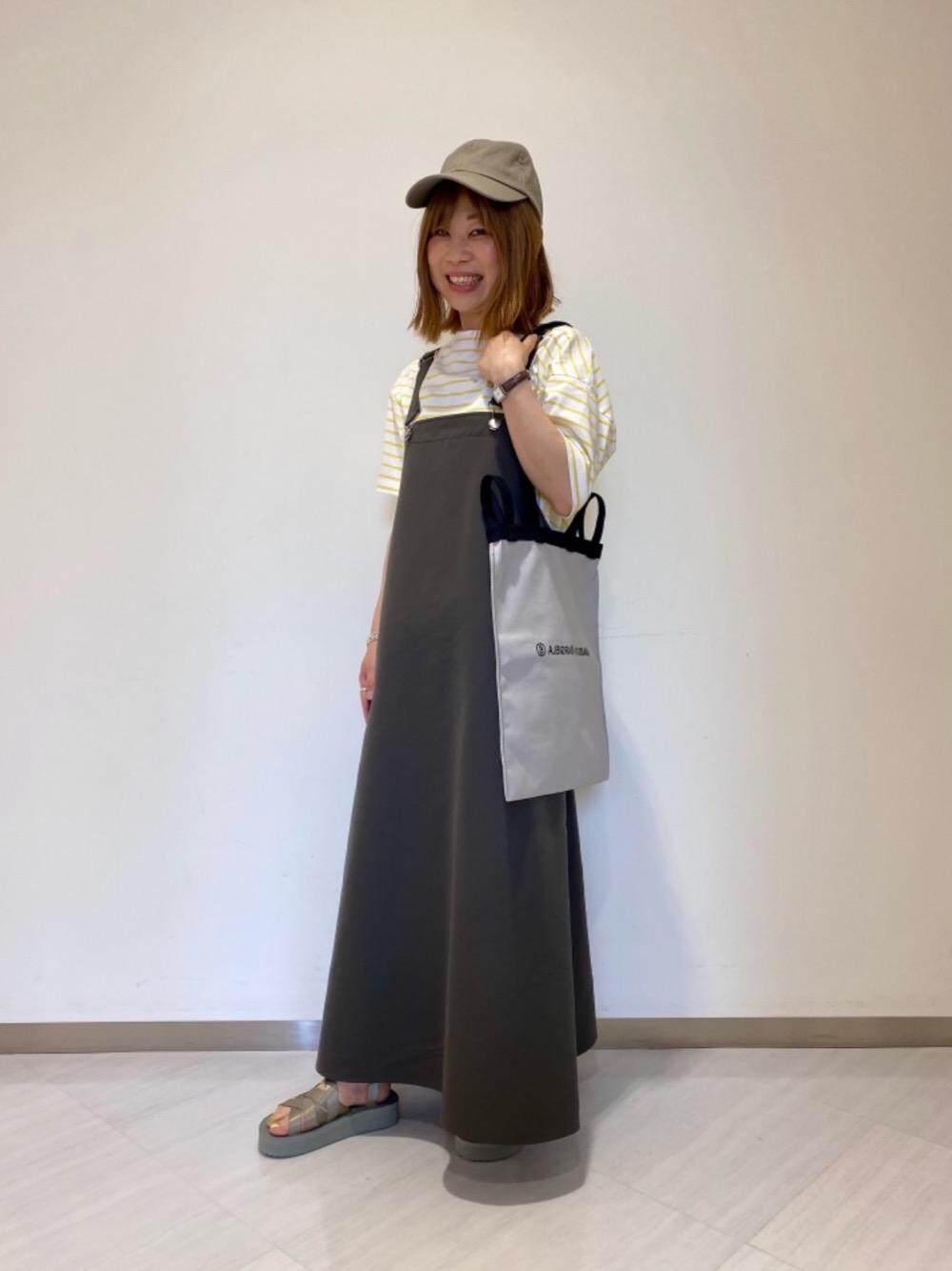 グレー系のサンダル、イエロー系のTシャツ/カットソー、グリーン系のキャップを着用したレディースの夏コーディネートの1枚目の写真