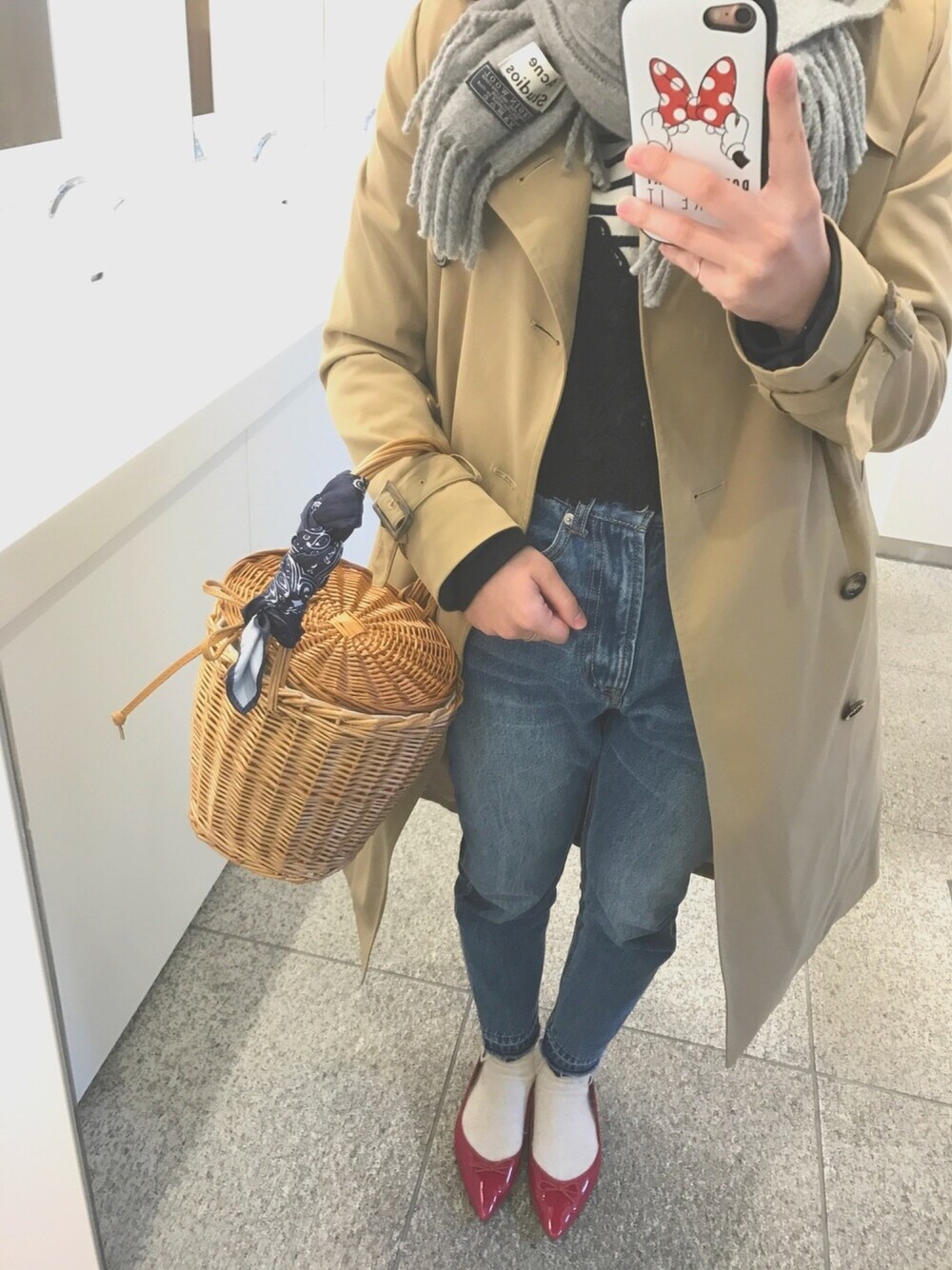 ベージュ系のトレンチコート、ブルー系のかごバッグ、ブルー系のデニムパンツを着用したレディースの春コーディネートの1枚目の写真