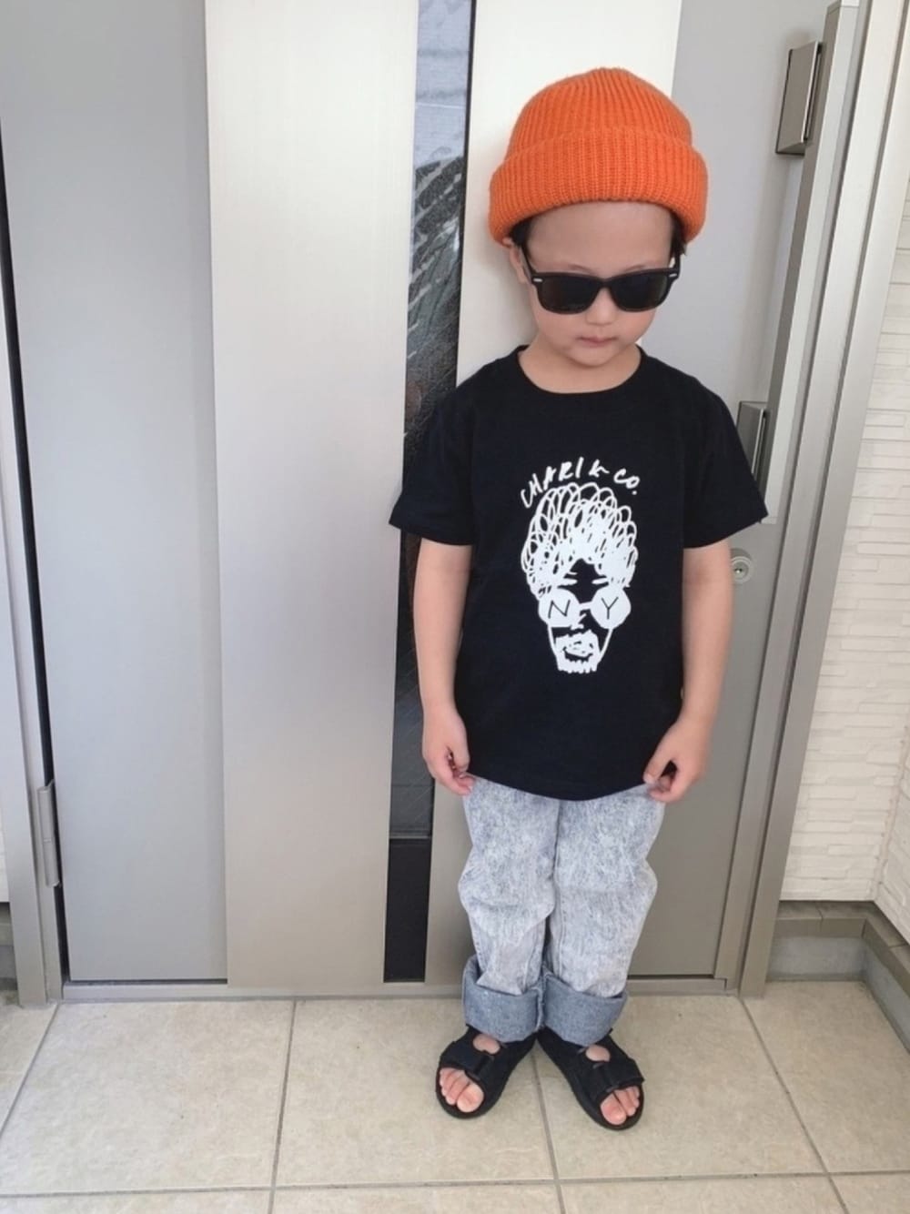 ブラック系のTシャツ/カットソー、ブルー系のデニムパンツ、ブラック系のサンダルを着用したキッズの春コーディネートの1枚目の写真