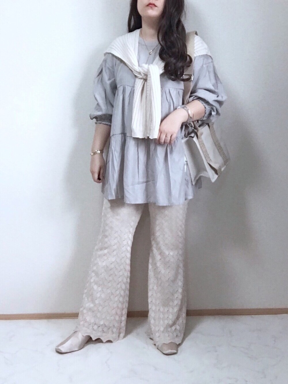 グレー系のチュニック、ホワイト系のパンツ、ホワイト系のバッグを着用したレディースの春コーディネートの1枚目の写真