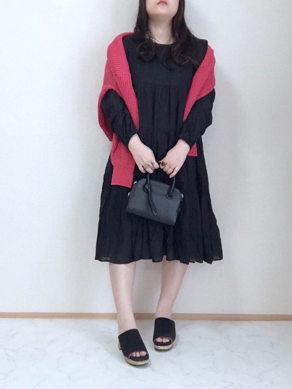 ブラック系のワンピース、レッド系のカーディガン/ボレロ、ブラック系のボストンバッグを着用したレディースの春コーディネートの1枚目の写真