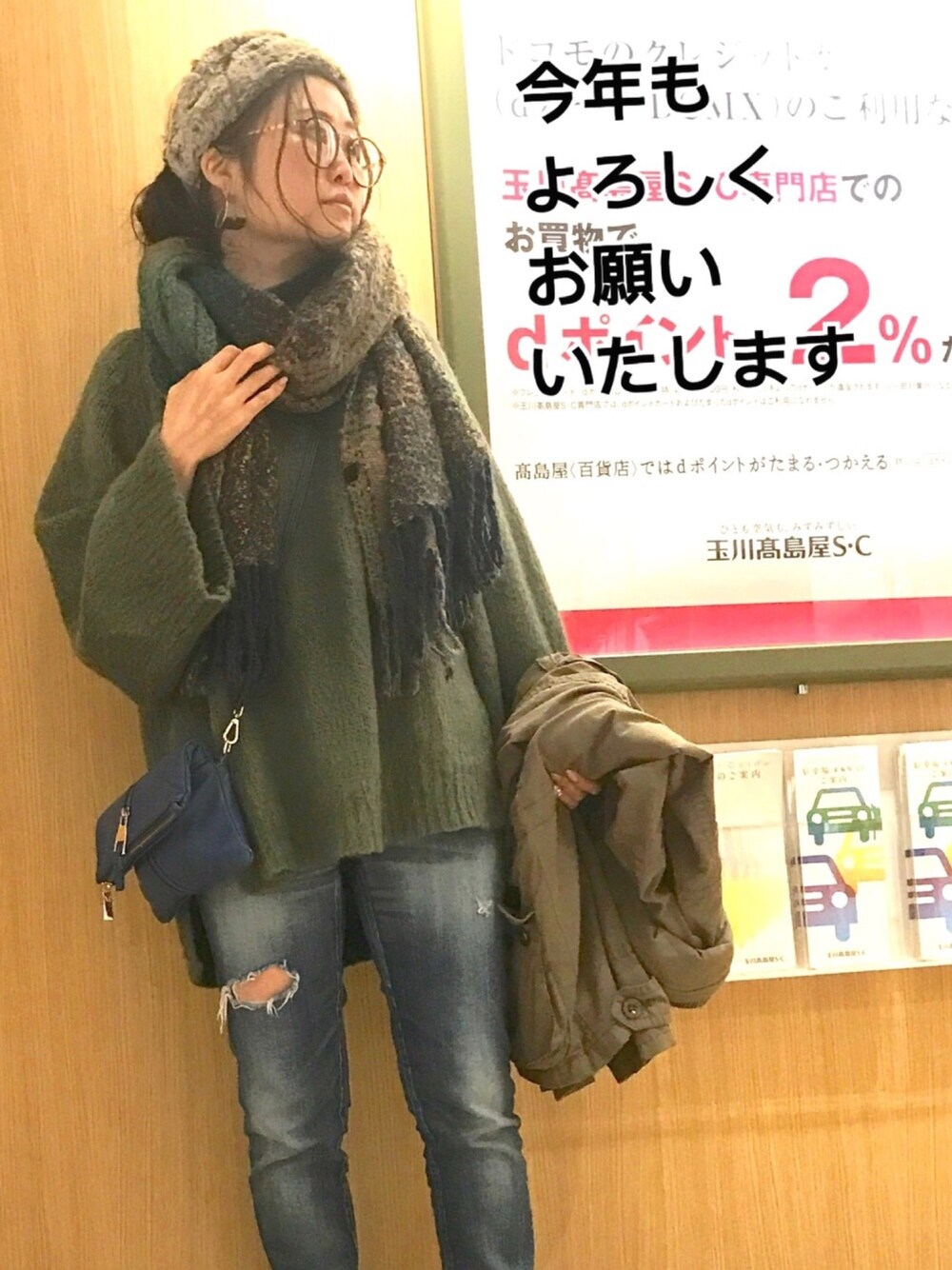 グリーン系のニット/セーター、ブルー系のデニムパンツ、ブルー系のショルダーバッグを着用したレディースの冬コーディネートの1枚目の写真