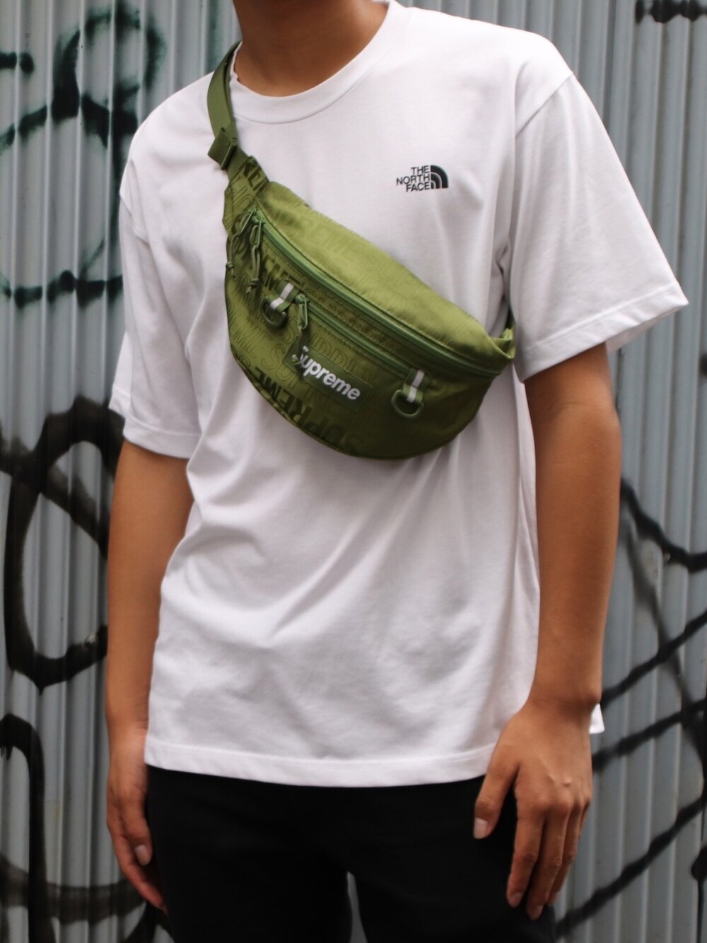 ホワイト系のTシャツ/カットソー、グリーン系のボディバッグ/ウエストポーチ、ブラック系のパンツを着用したメンズの夏コーディネートの1枚目の写真