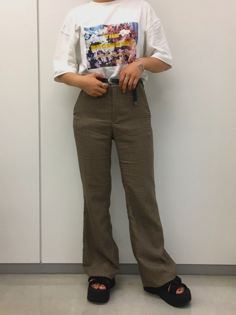 ホワイト系のTシャツ/カットソー、ブラウン系のパンツ、ブラック系のサンダルを着用したレディースの秋コーディネートの1枚目の写真