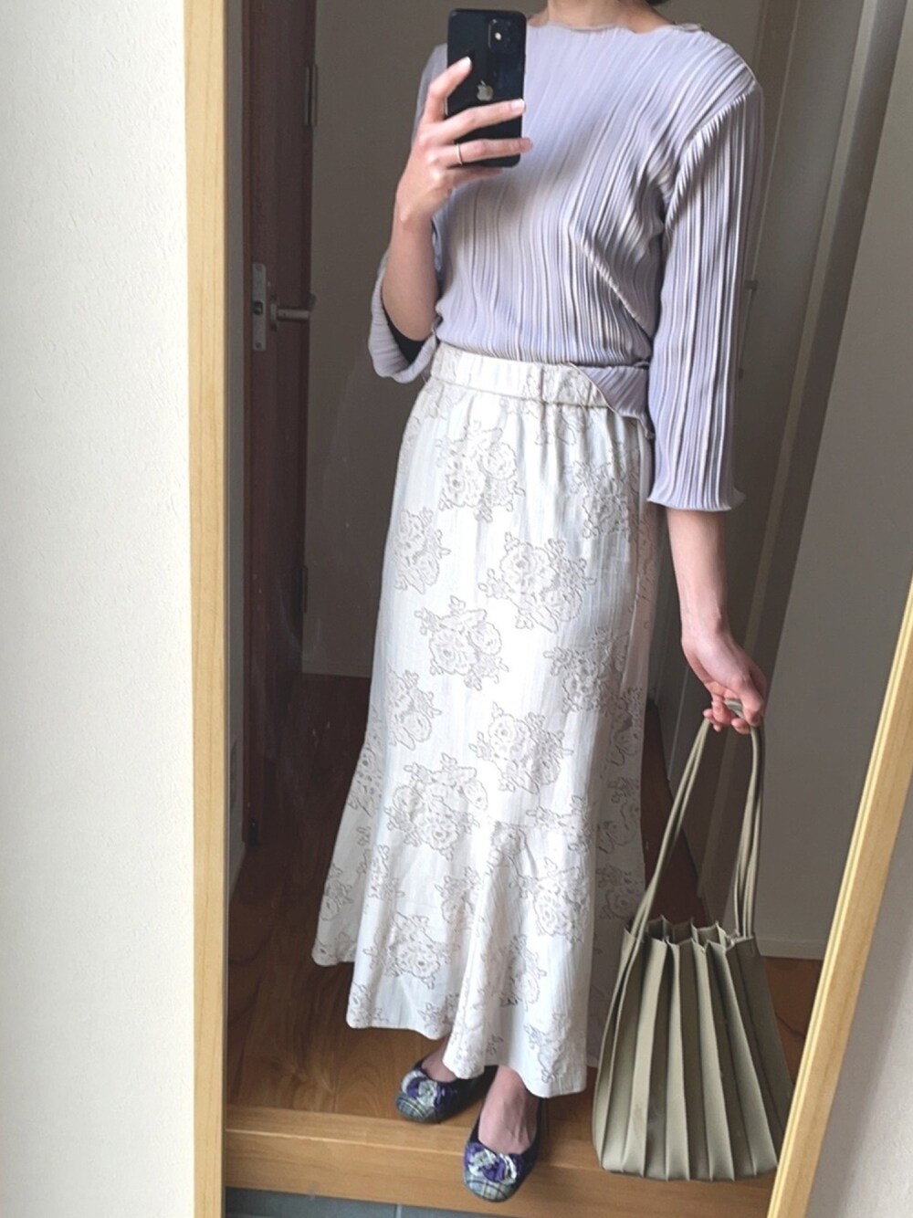 グリーン系のトートバッグ、ベージュ系のスカート、パープル系のTシャツ/カットソーを着用したレディースの春コーディネートの1枚目の写真