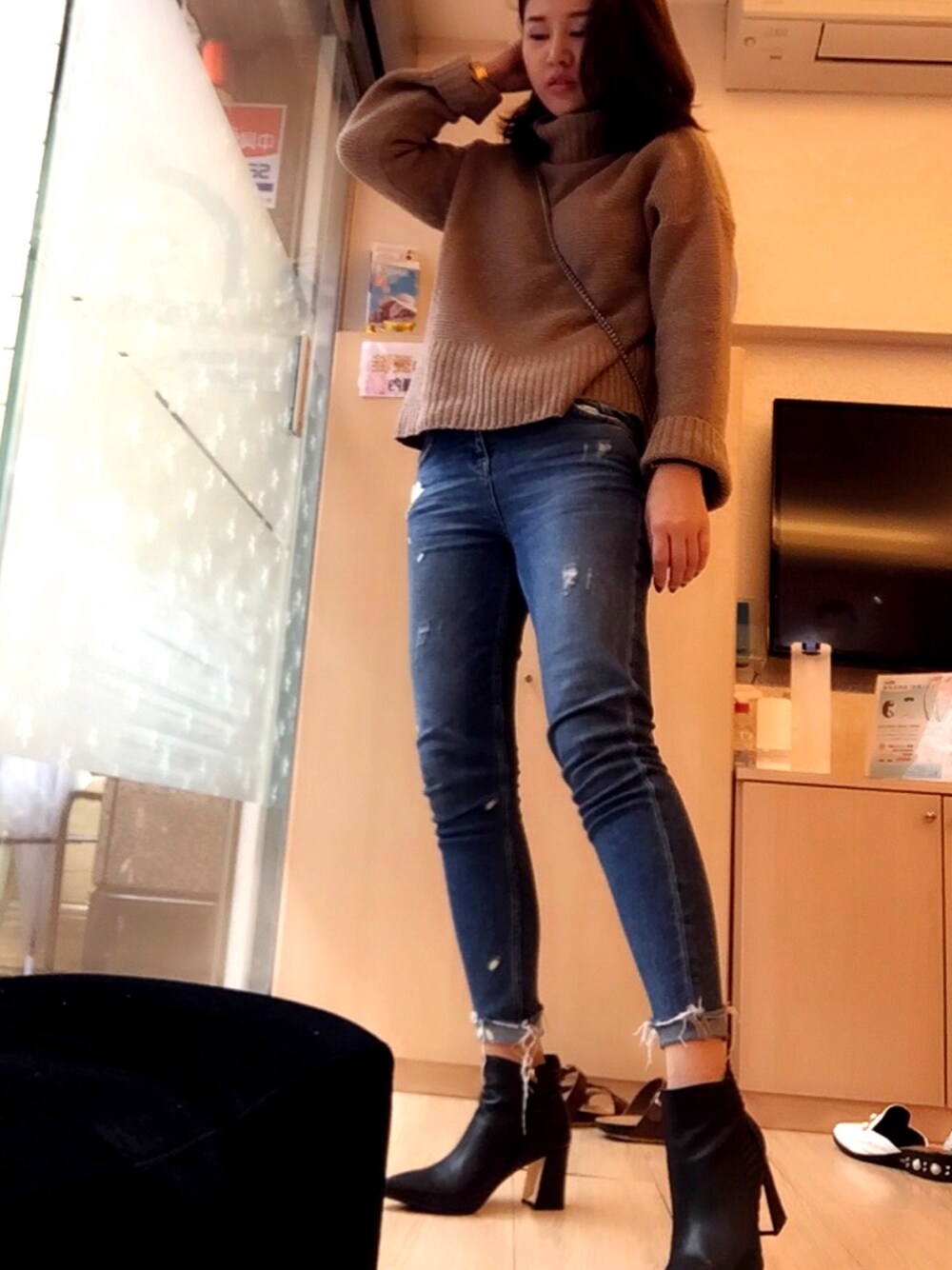 ブルー系のデニムパンツ、ブラウン系のニット/セーター、ブラック系のブーティを着用したレディースの冬コーディネートの1枚目の写真