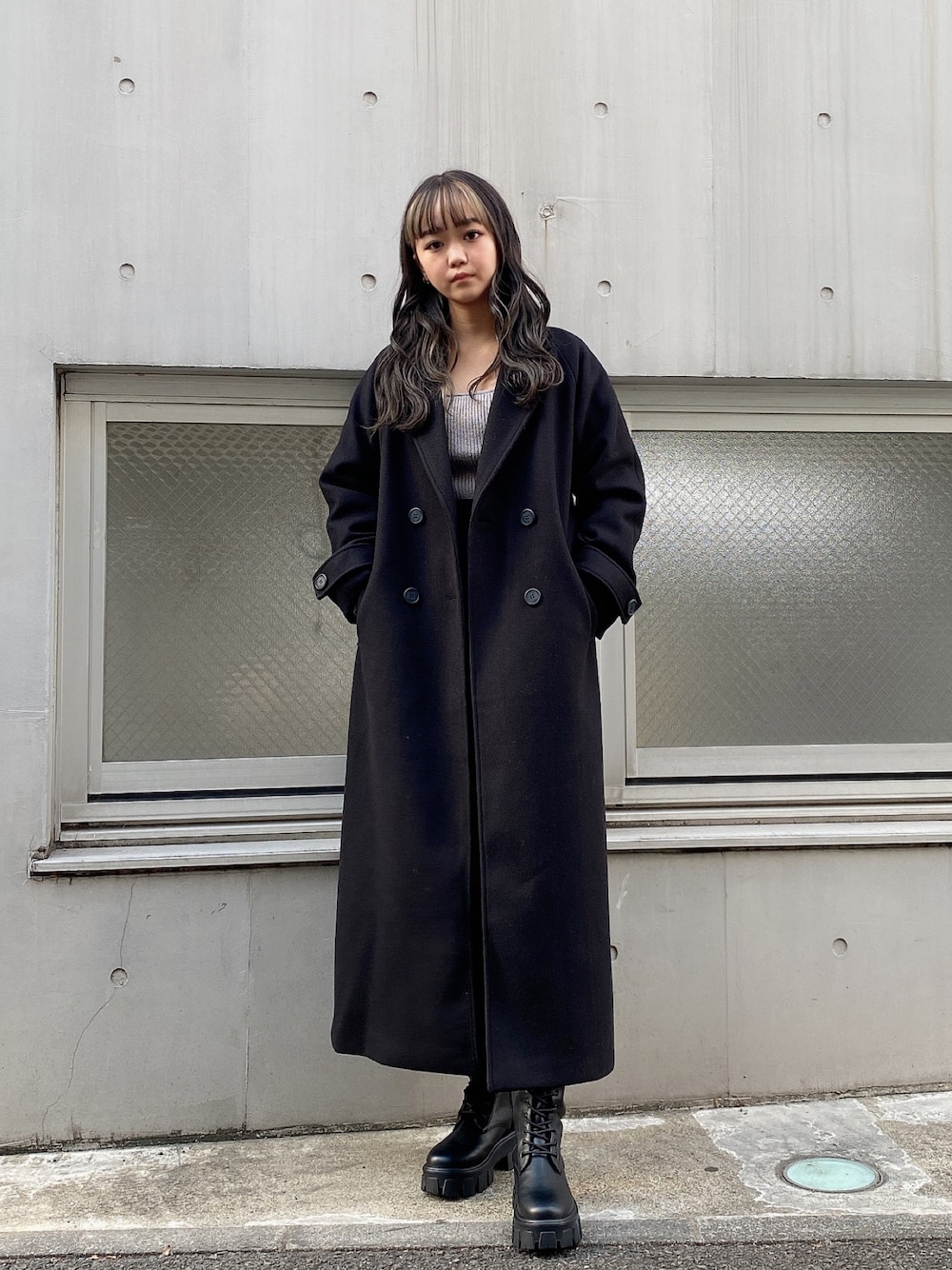 ブラック系のチェスターコート、グレー系のニット/セーター、ブラック系のスカートを着用したレディースの冬コーディネートの1枚目の写真