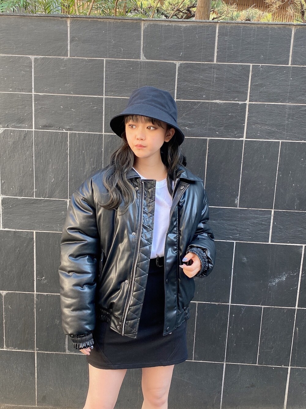 ブラック系のその他アウター、ホワイト系のTシャツ/カットソー、ブラック系のスカートを着用したレディースの冬コーディネートの1枚目の写真