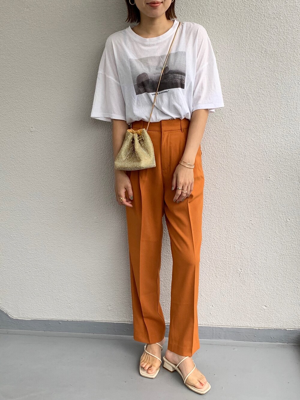 オレンジ系のスラックスを着用したレディースの夏コーディネートの1枚目の写真