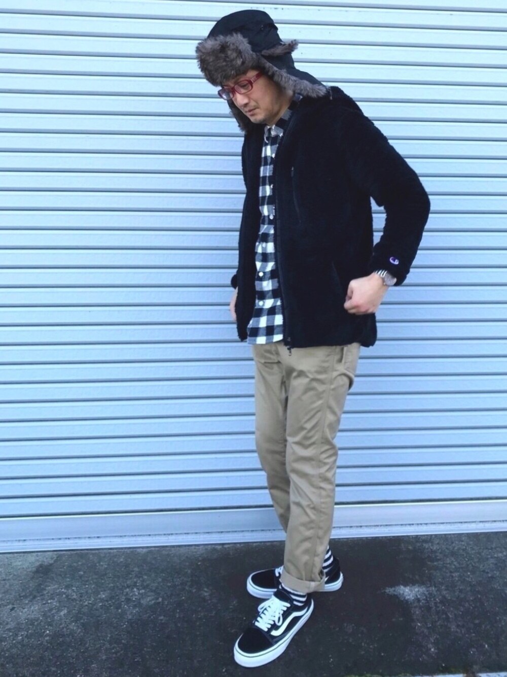 ブラック系のパーカー、ホワイト系のトップス、ベージュ系のチノパンツを着用したメンズの冬コーディネートの1枚目の写真