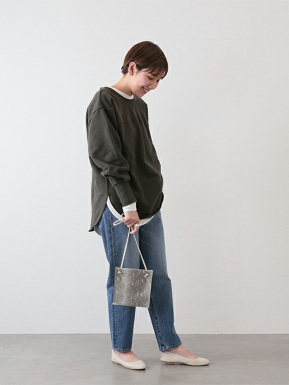 ブラック系のスウェット、ホワイト系のTシャツ/カットソー、ブルー系のデニムパンツを着用したレディースの冬コーディネートの1枚目の写真