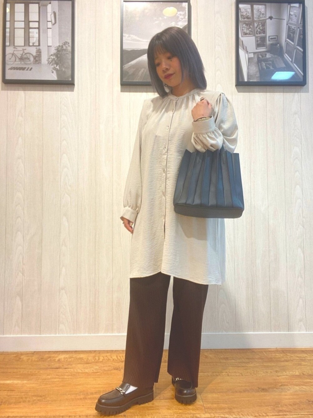 ベージュ系のチュニック、ブラック系のバッグ、ブラック系のドレスシューズを着用したレディースの春コーディネートの1枚目の写真