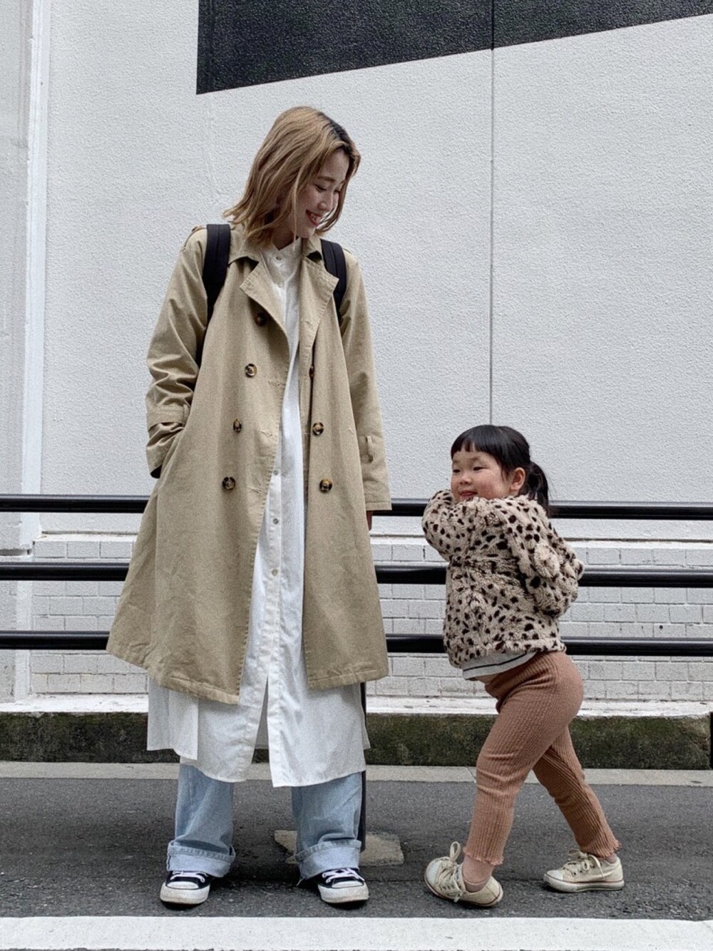 ベージュ系のトレンチコート、ブルー系のデニムパンツ、ブラック系のスニーカーを着用したレディースの春コーディネートの1枚目の写真