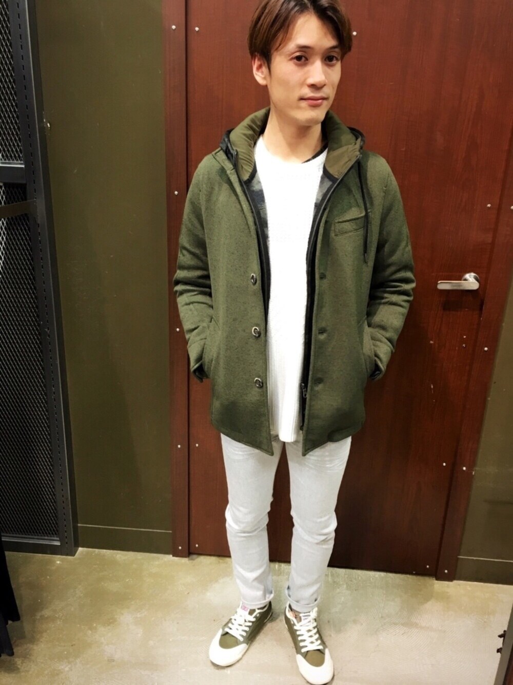 グリーン系のカバーオール、ホワイト系のニット/セーター、グリーン系のスニーカーを着用したメンズの冬コーディネートの1枚目の写真