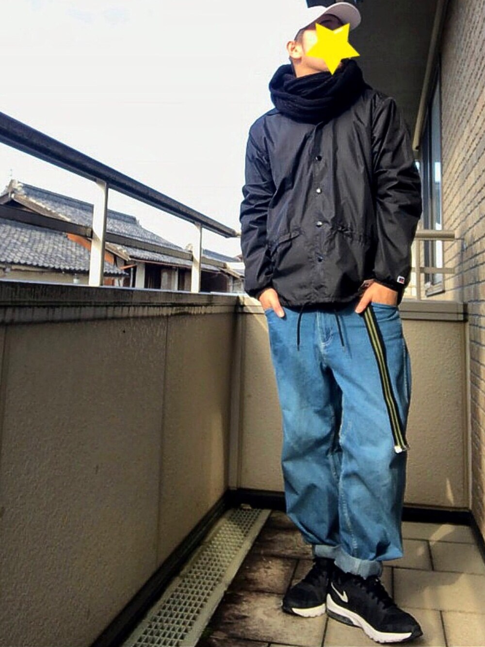 ブルー系のデニムパンツ、ブラック系のパーカー、ブラック系のナイロンジャケットを着用したメンズの冬コーディネートの1枚目の写真