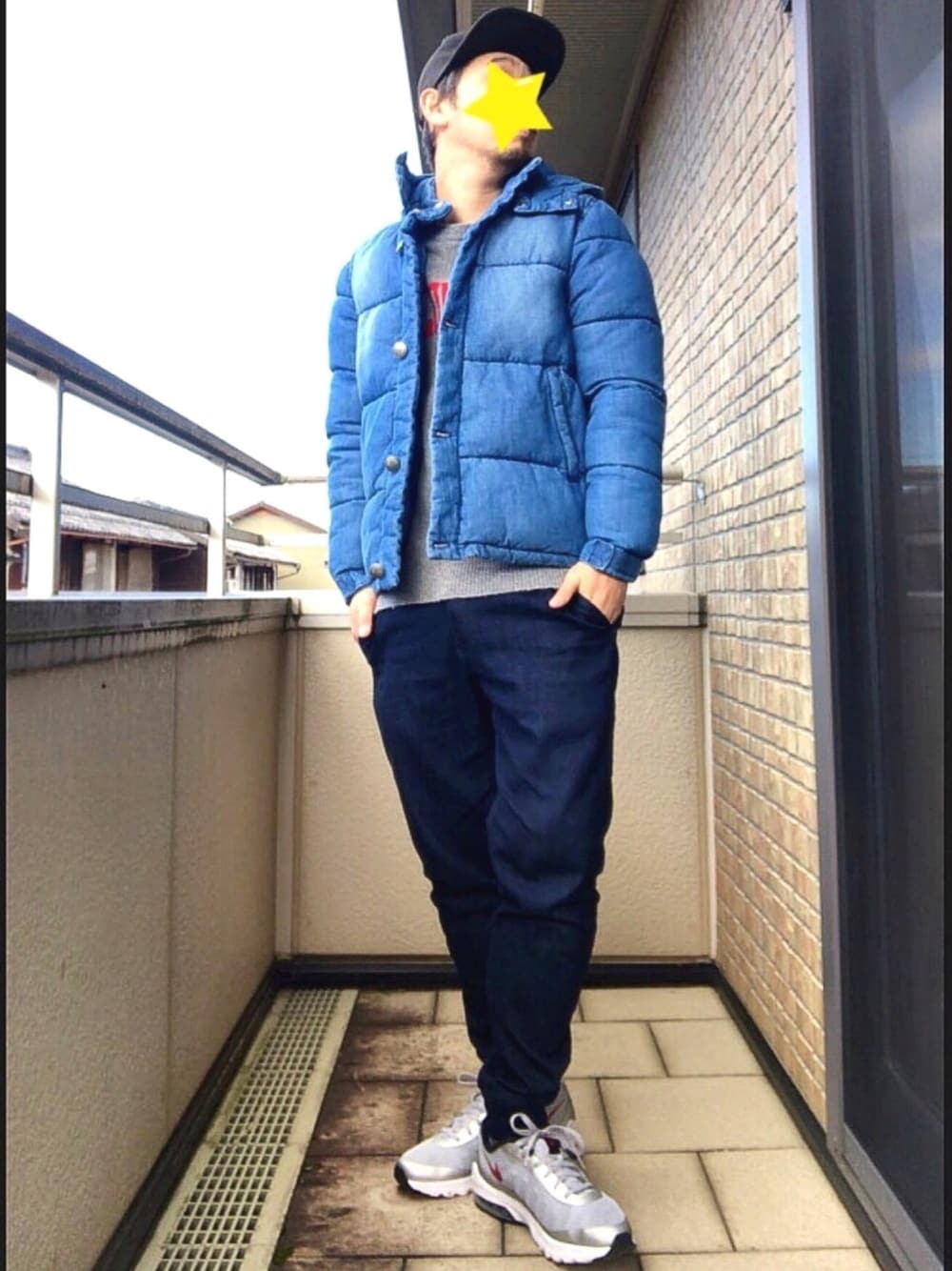 グレー系のニット/セーター、ブルー系のダウンジャケット/コート、ブルー系のデニムパンツを着用したメンズの冬コーディネートの1枚目の写真