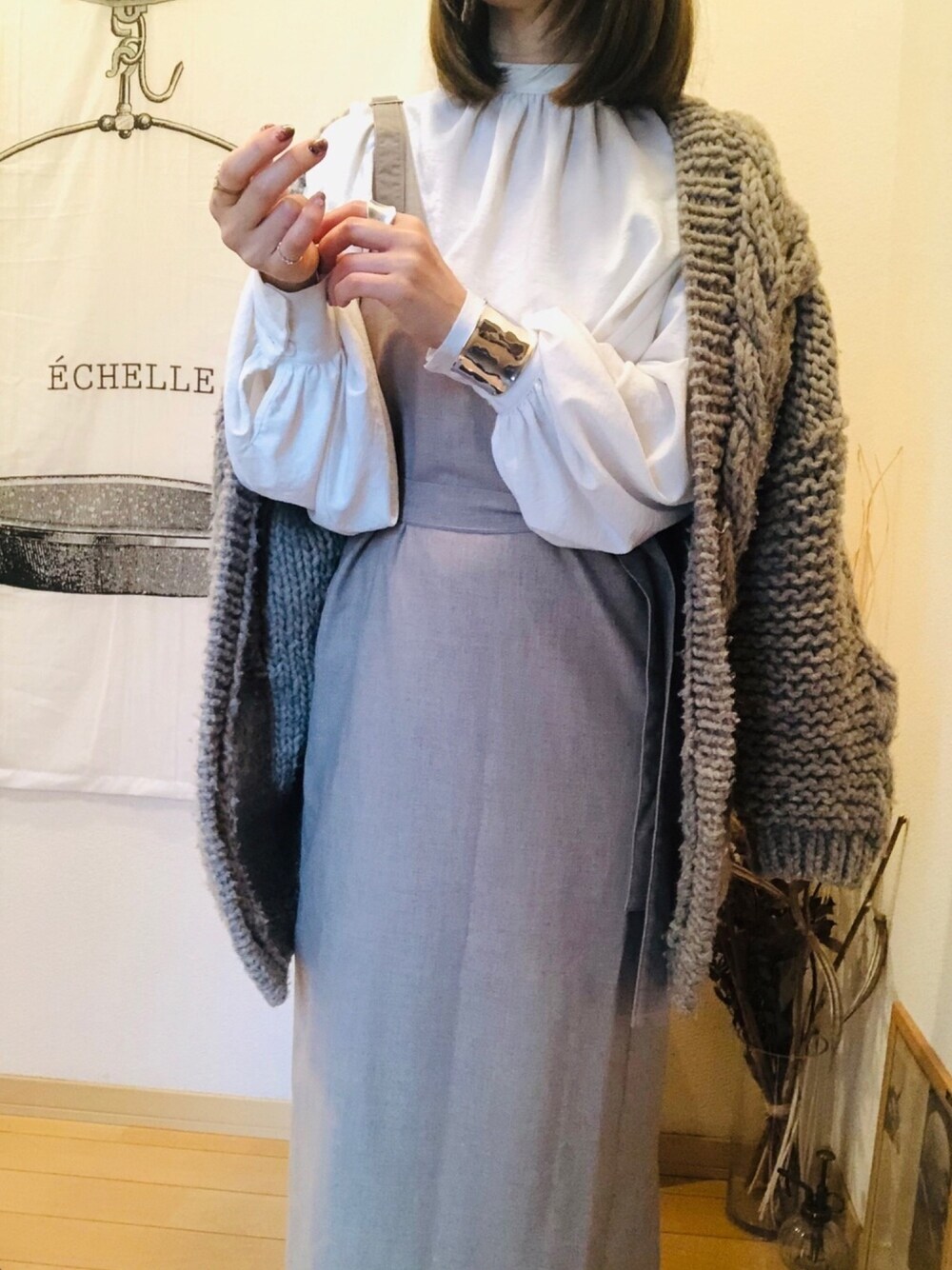 グレー系のカーディガン/ボレロ、ホワイト系のシャツ/ブラウス、グレー系のワンピース/ドレスを着用したレディースの冬コーディネートの1枚目の写真