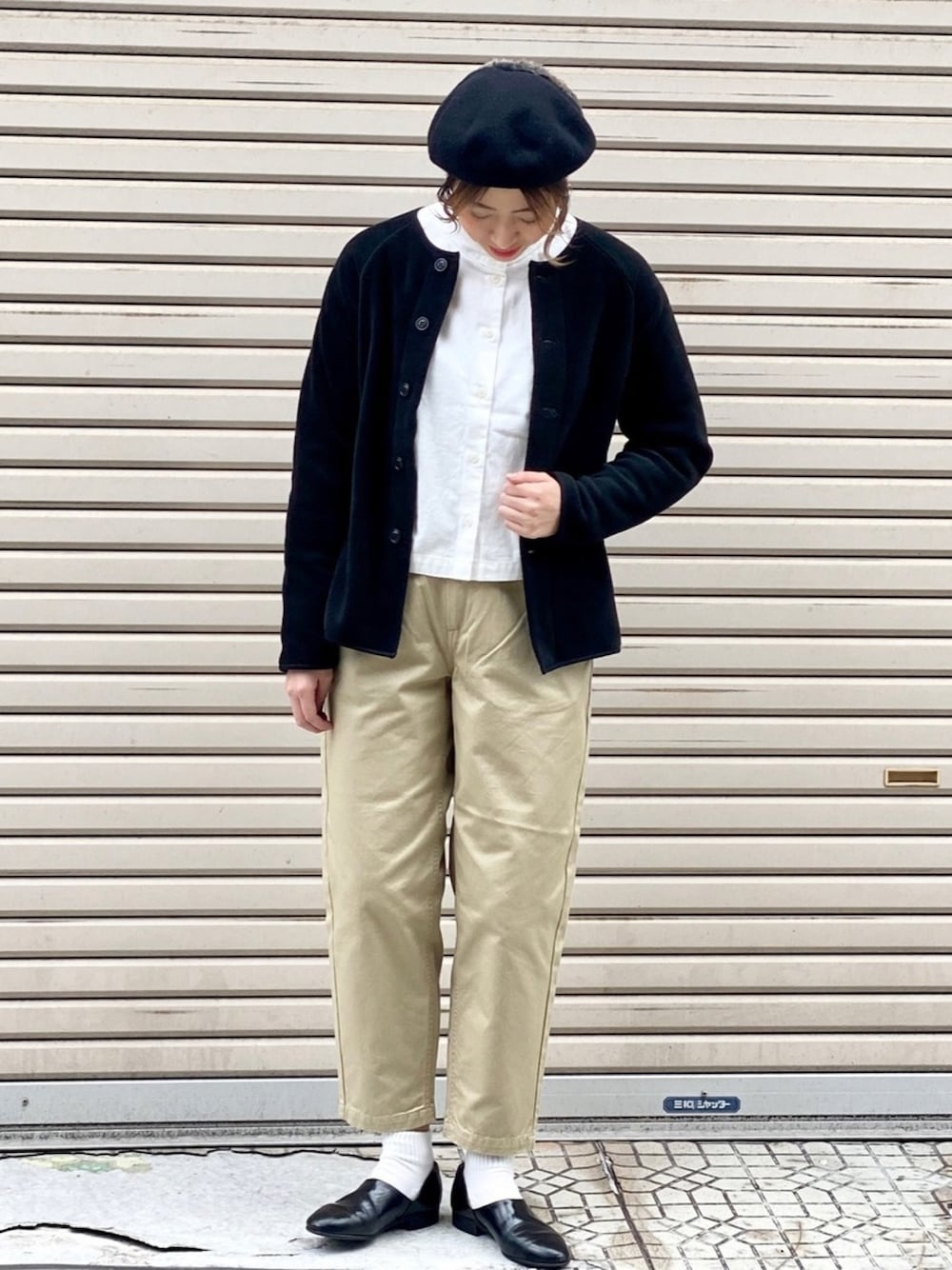 ブラック系のカーディガン/ボレロ、ホワイト系のシャツ/ブラウス、ベージュ系のチノパンツを着用したレディースの冬コーディネートの1枚目の写真