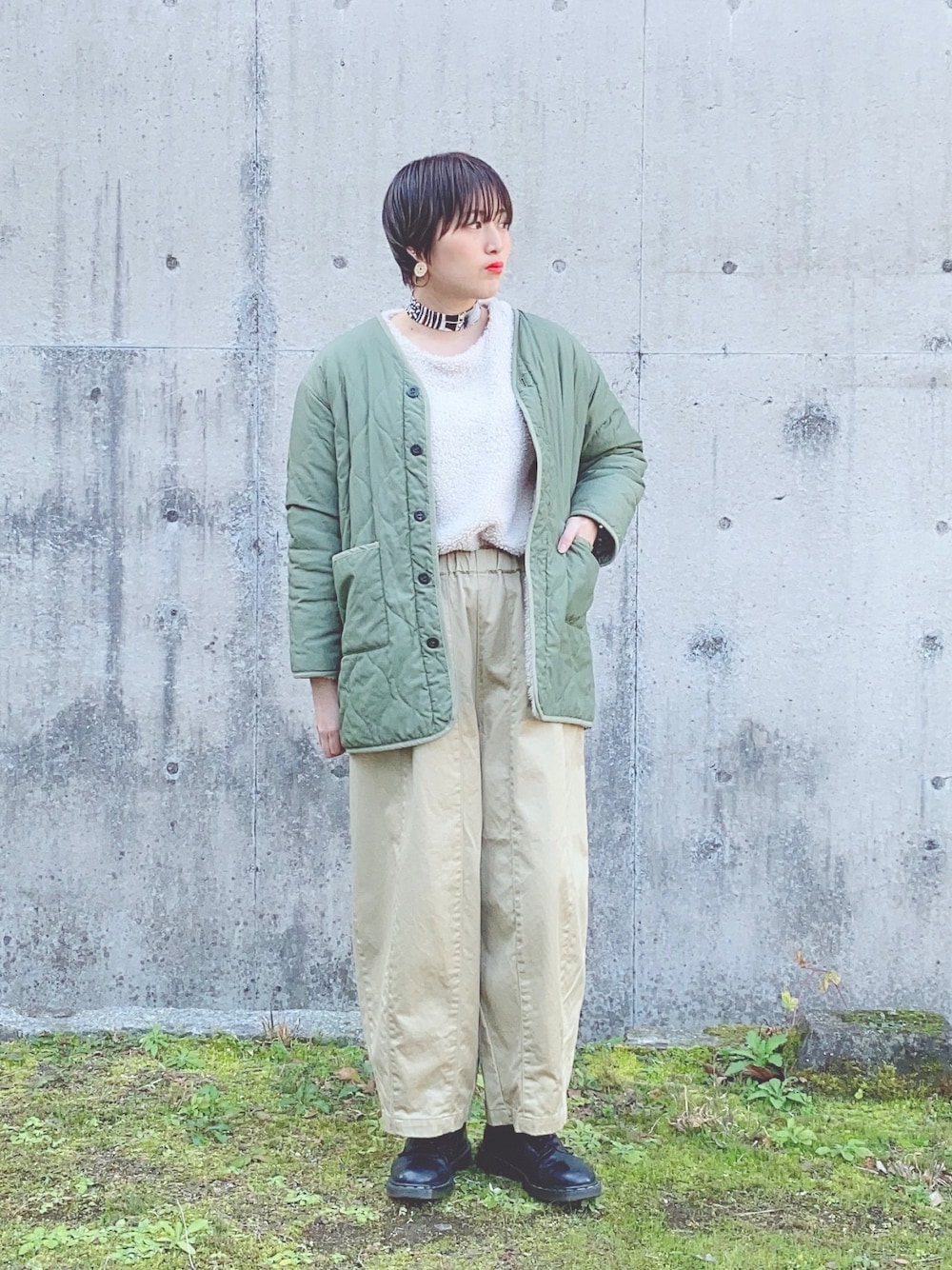 グリーン系のミリタリージャケット、ホワイト系のトップス、ベージュ系のその他パンツを着用したレディースの冬コーディネートの1枚目の写真