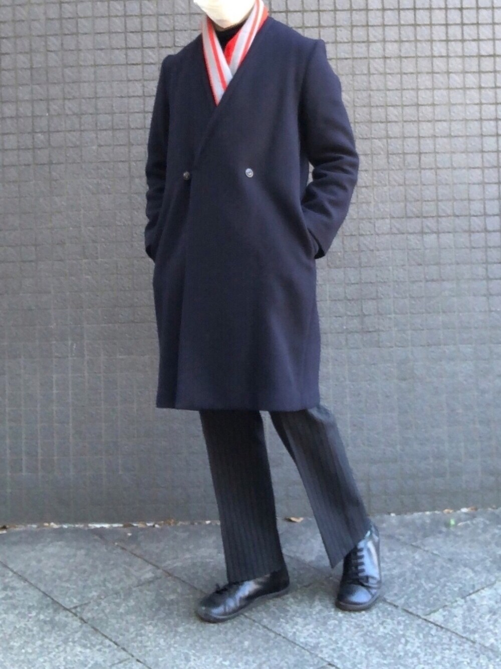 ブルー系のノーカラーコート、グレー系のスラックス、ブラック系のスニーカーを着用したメンズの冬コーディネートの1枚目の写真