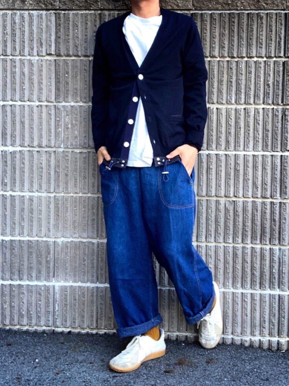 ブルー系のニット/セーター、ブルー系のデニムパンツ、ベージュ系のスニーカーを着用したメンズの春コーディネートの1枚目の写真