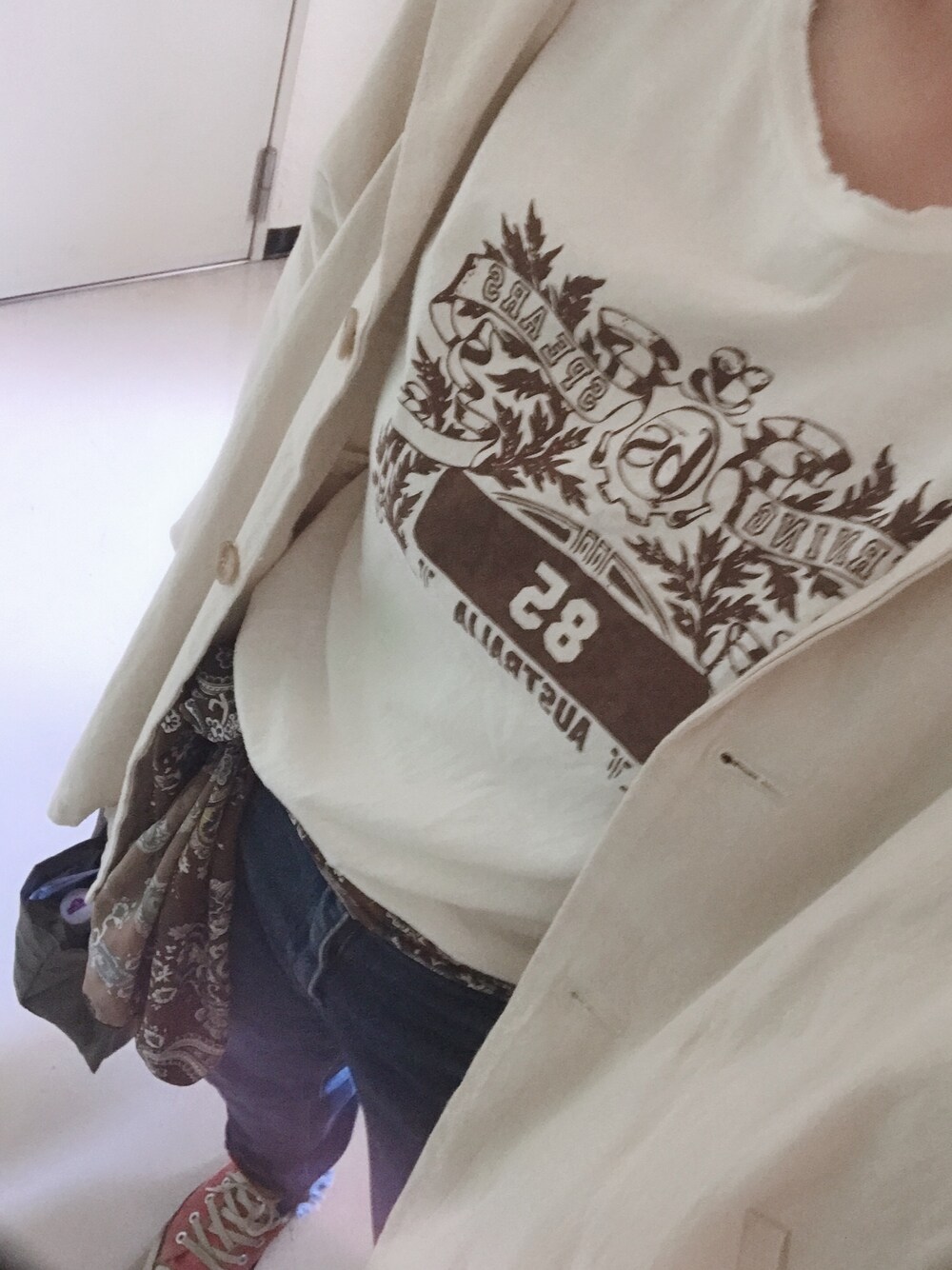 ホワイト系のノーカラージャケット、ブルー系のデニムパンツ、レッド系のスニーカーを着用したレディースの春コーディネートの1枚目の写真