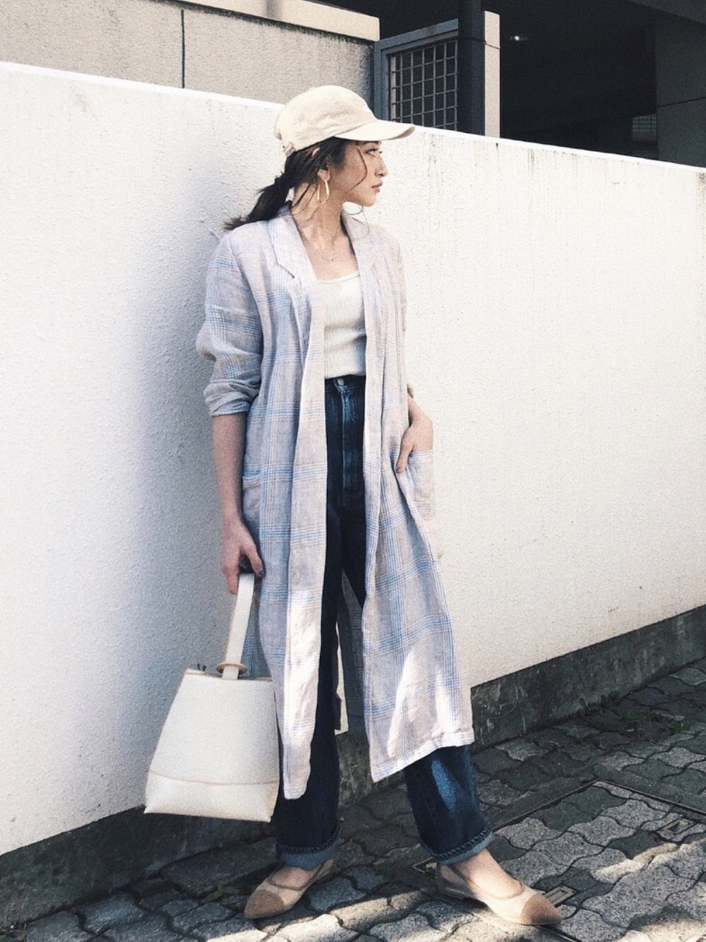 ブルー系のデニムパンツ、ベージュ系のその他シューズ、ホワイト系のハンドバッグを着用したレディースの春コーディネートの1枚目の写真