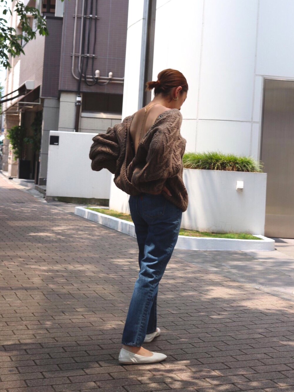 ブラウン系のニット/セーター、ブルー系のデニムパンツ、ホワイト系のバレエシューズを着用したレディースの秋コーディネートの1枚目の写真