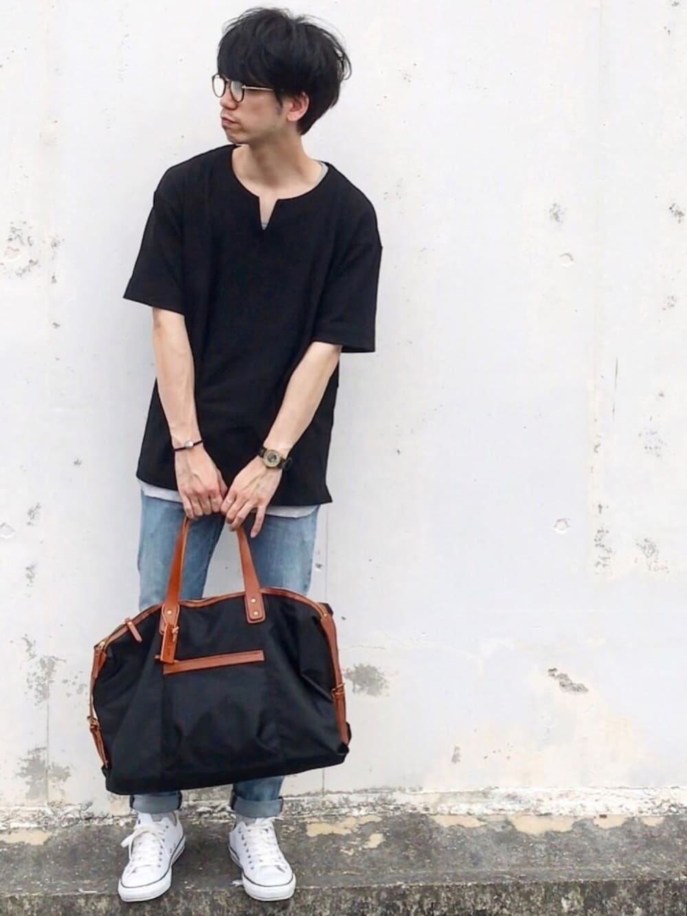 ブラック系のボストンバッグ、ブルー系のデニムパンツ、ホワイト系のスニーカーを着用したメンズの春コーディネートの1枚目の写真