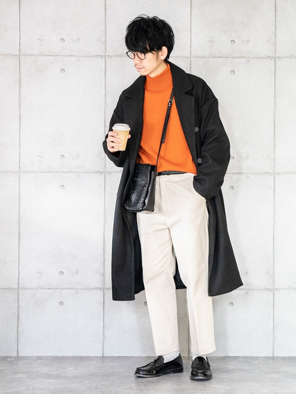 ブラック系のトレンチコート、オレンジ系のニット/セーター、ベージュ系のその他パンツを着用したメンズの秋コーディネートの1枚目の写真